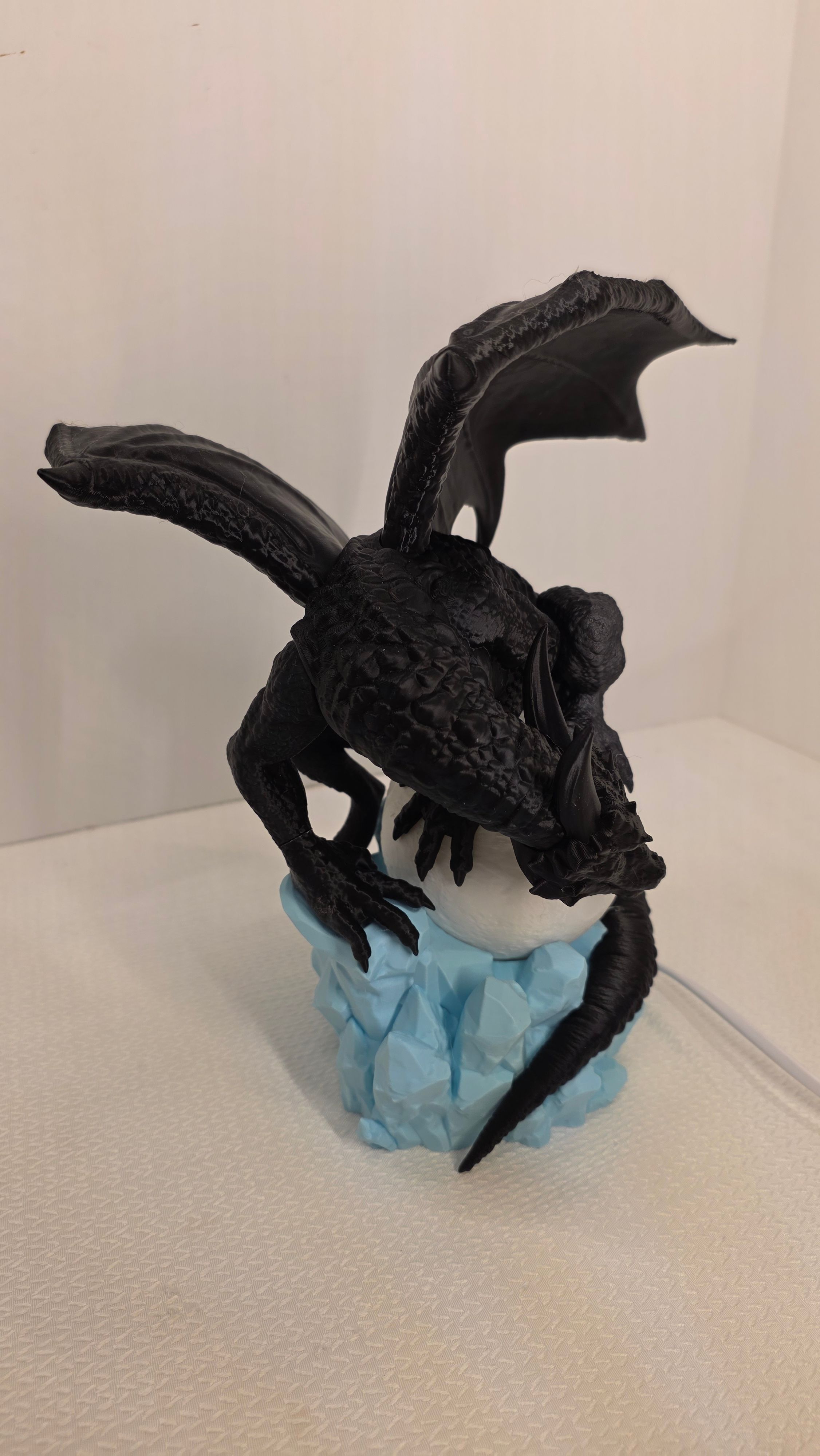Black dragon holding white moon sphere on blue crystal base