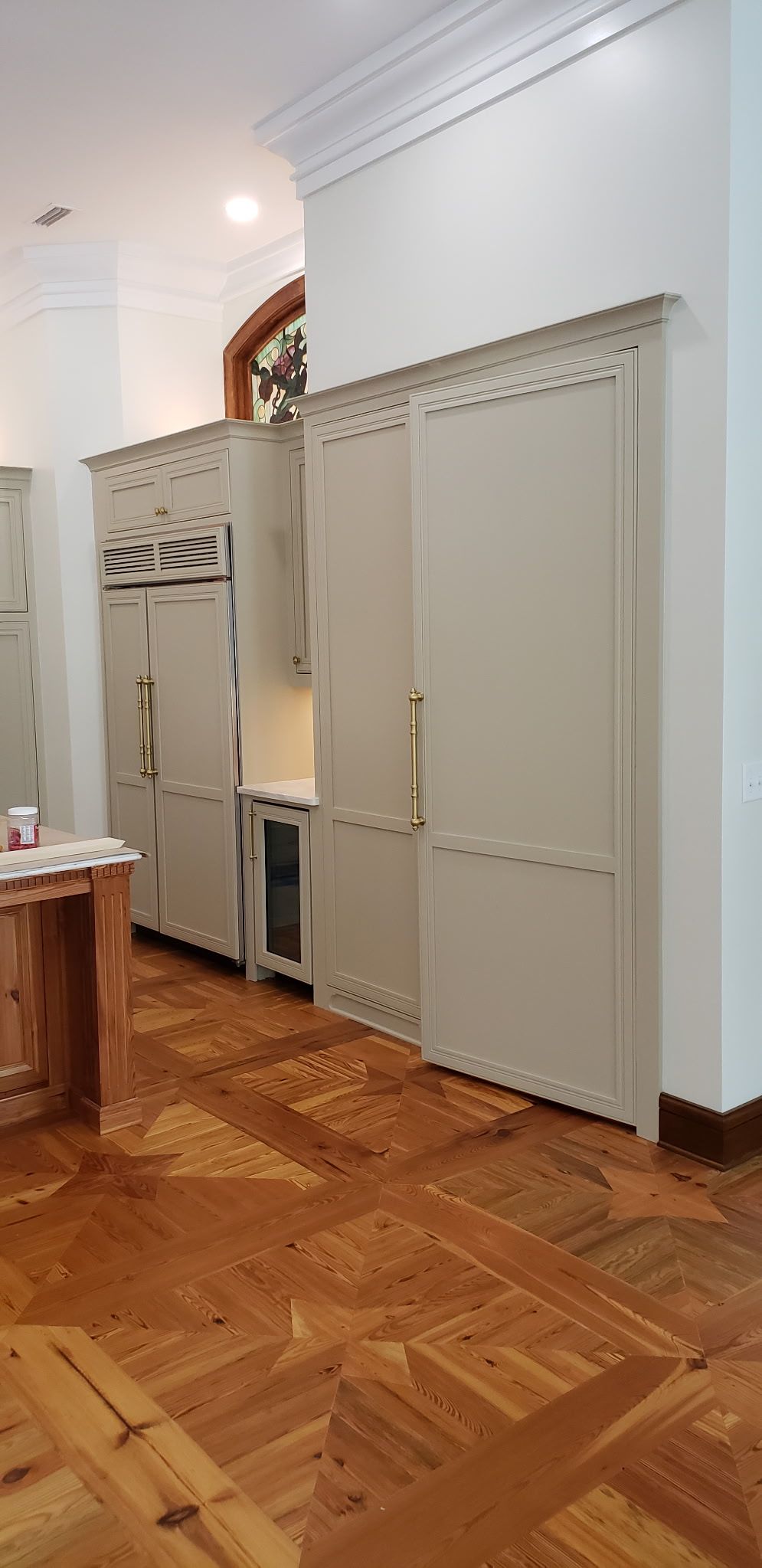 Beige cabinetry with gold handles and stained glass window