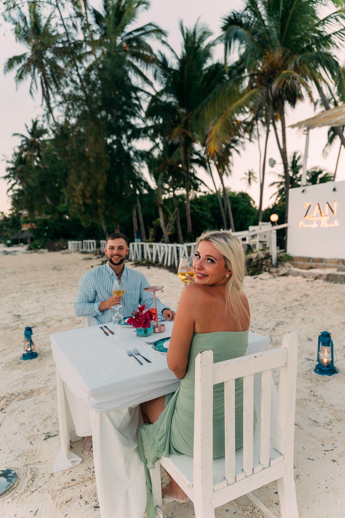 Couple enjoying romantic dinner on Zanzibar beach with blue lanterns