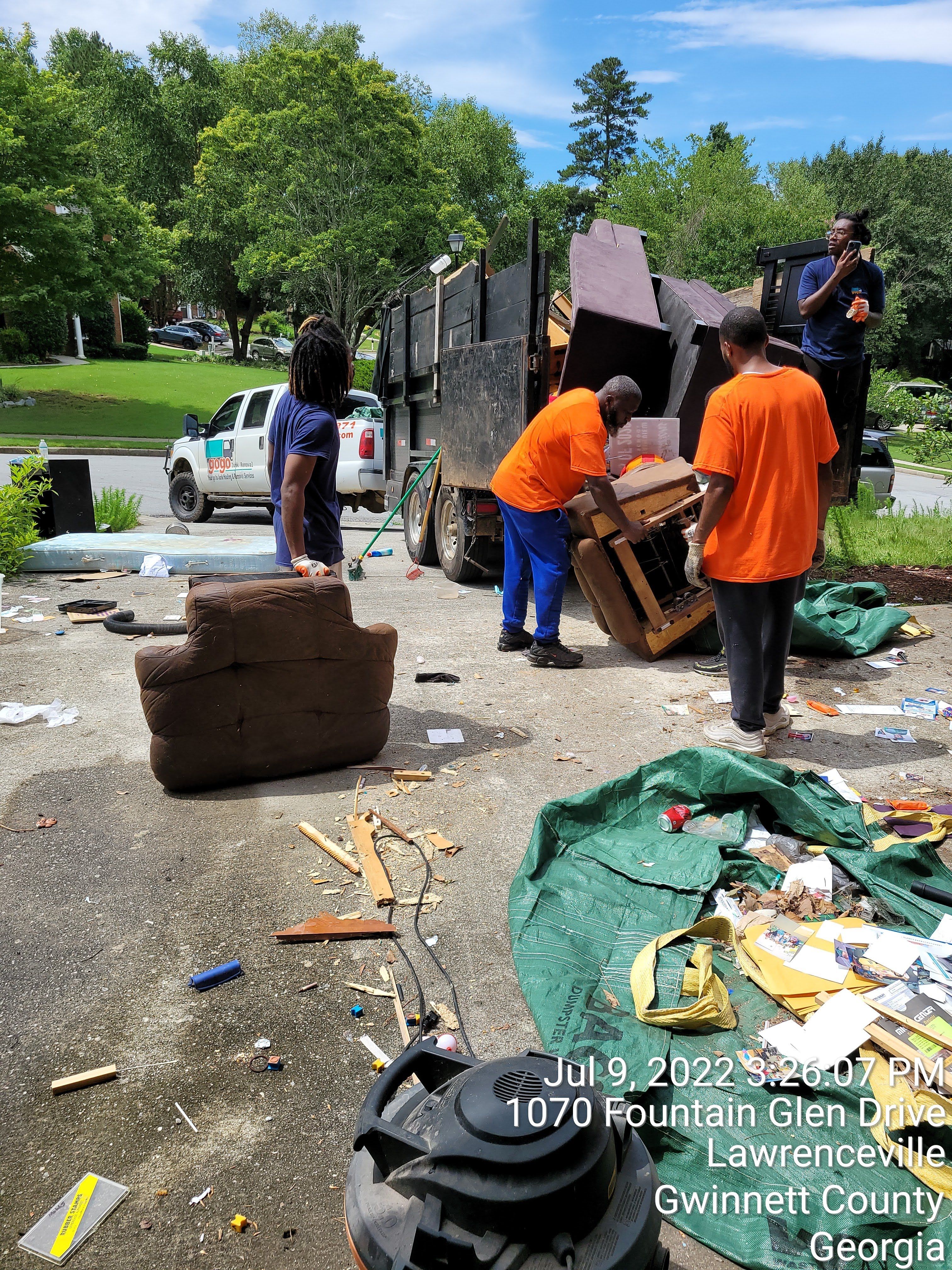 GoGo Junk Removal team handling furniture and debris on residential driveway