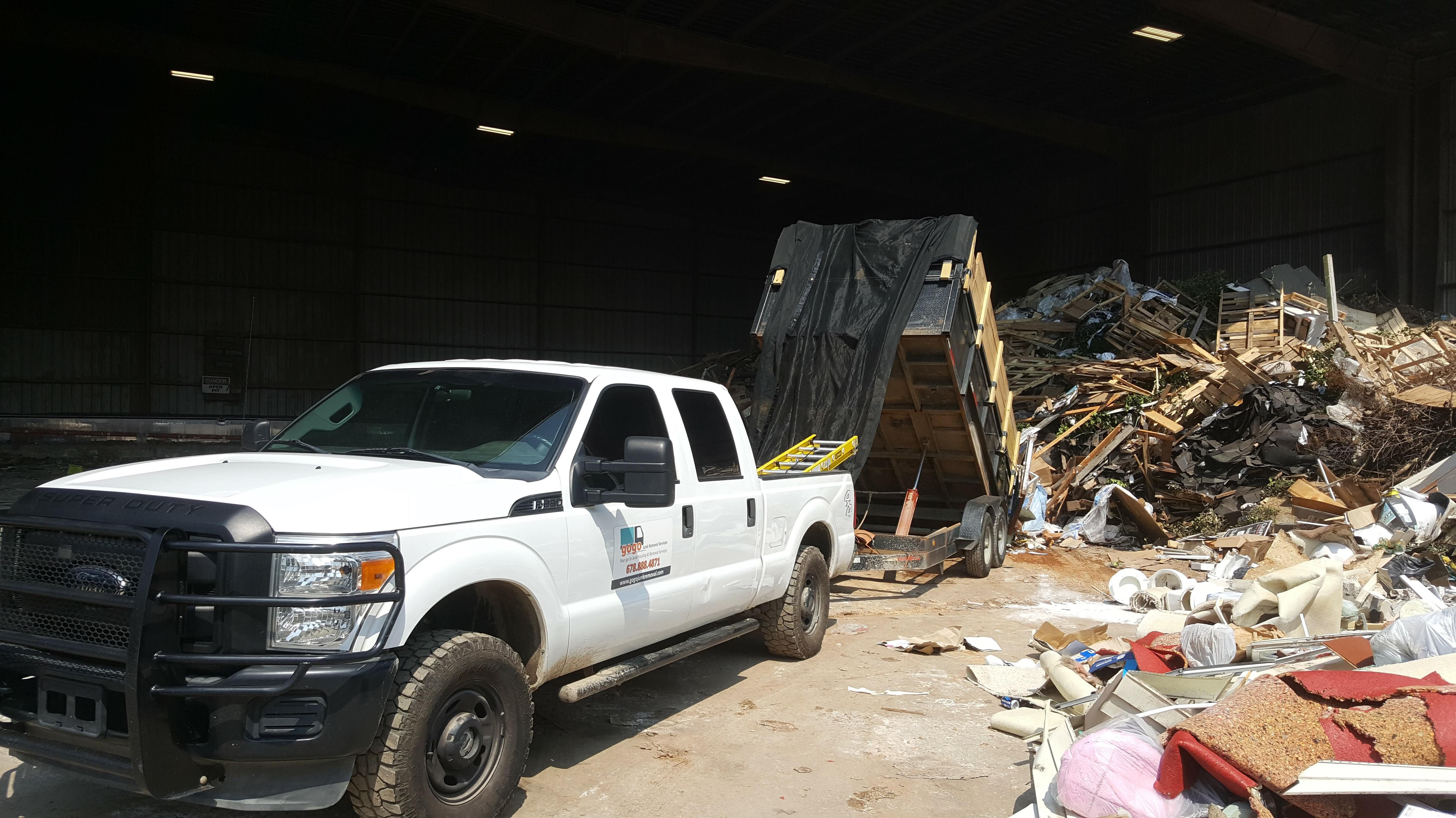 GoGo truck at warehouse - white GoGo Junk Removal pickup at industrial transfer station unloading debris