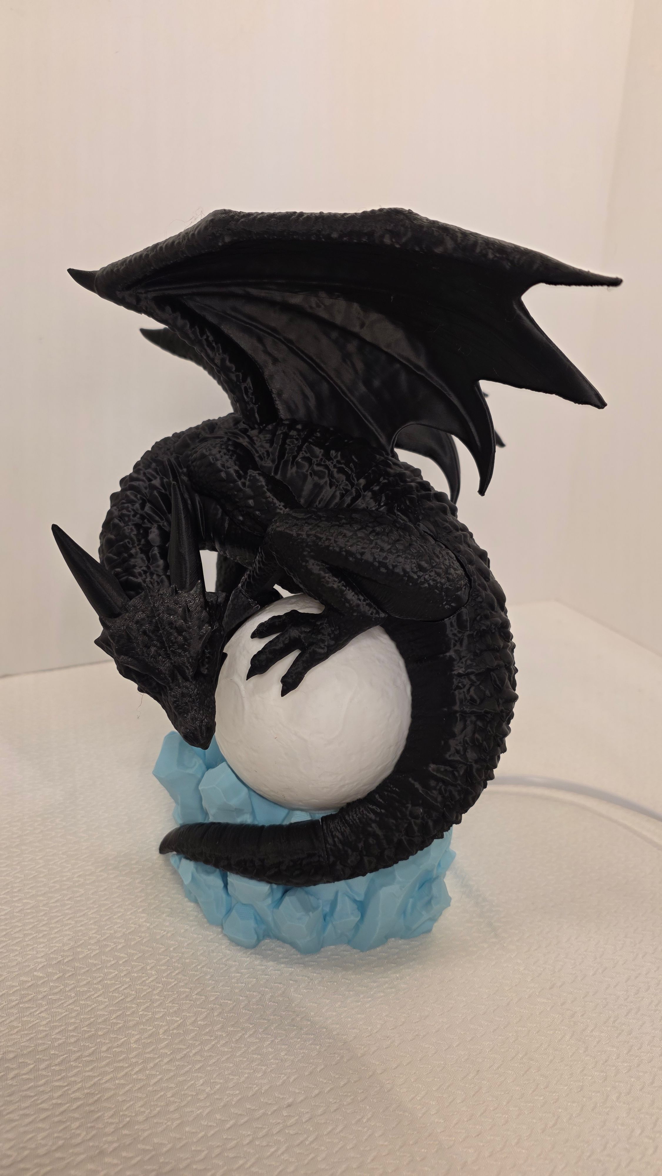 Black dragon curled around glowing moon with blue crystal base