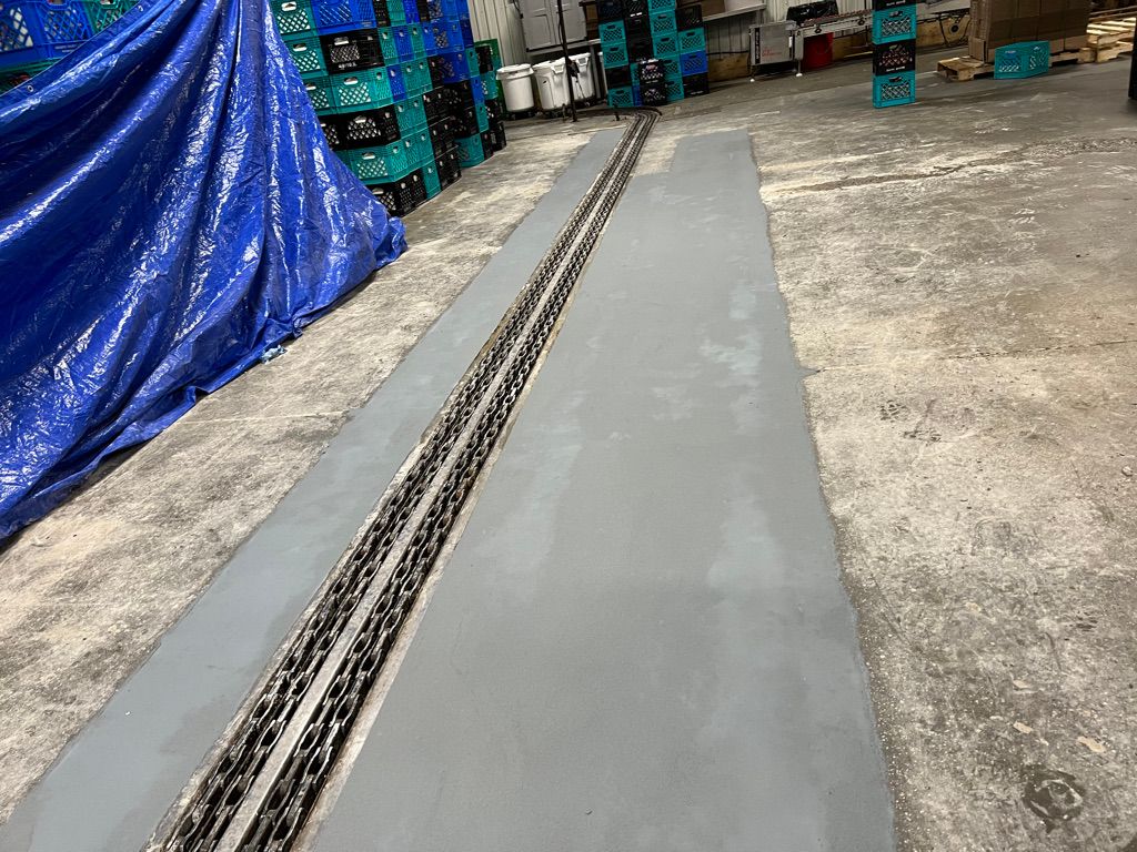 Concrete trench repair with polymer concrete flanking embedded track system in food facility