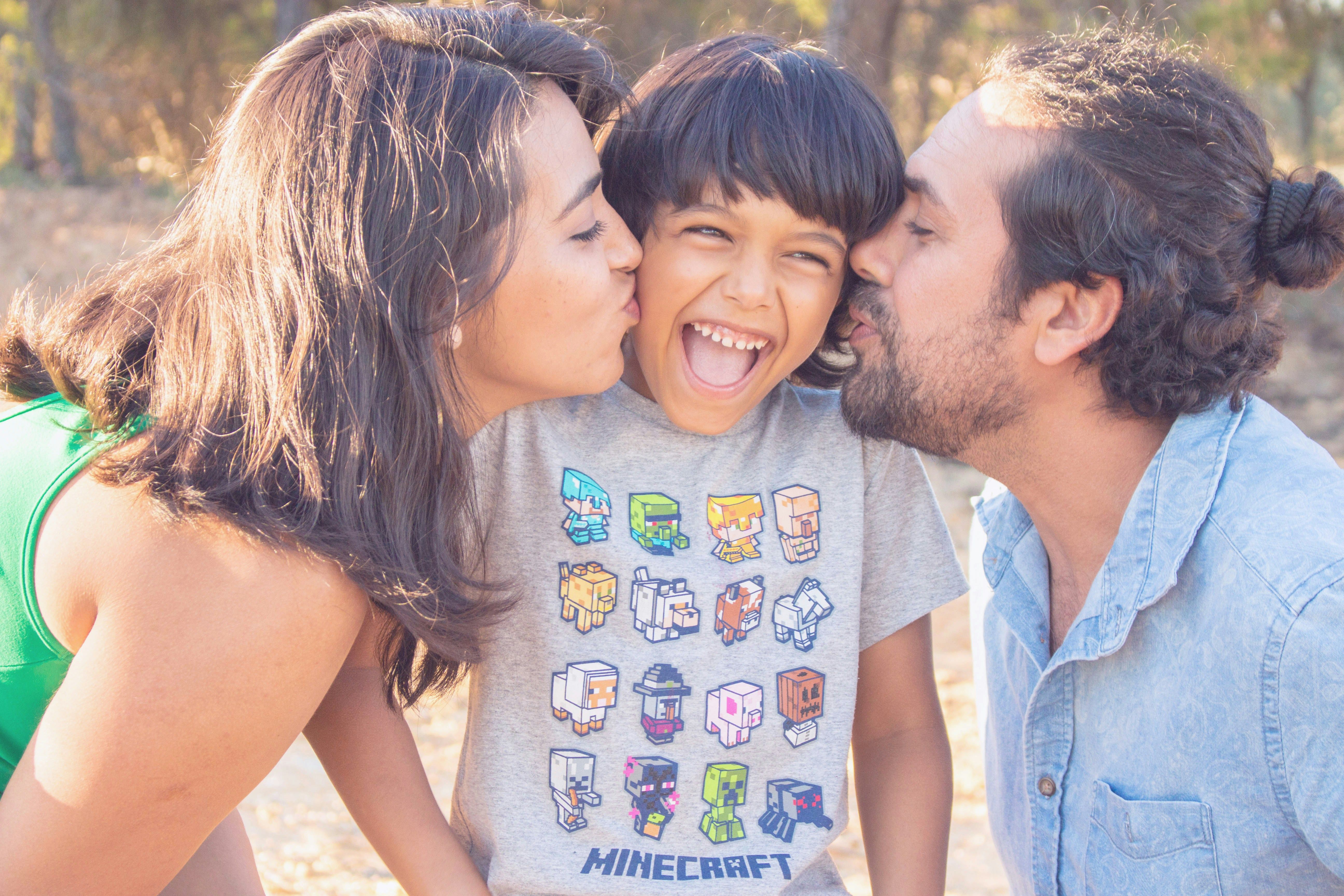Parents kissing their happy son on both cheeks