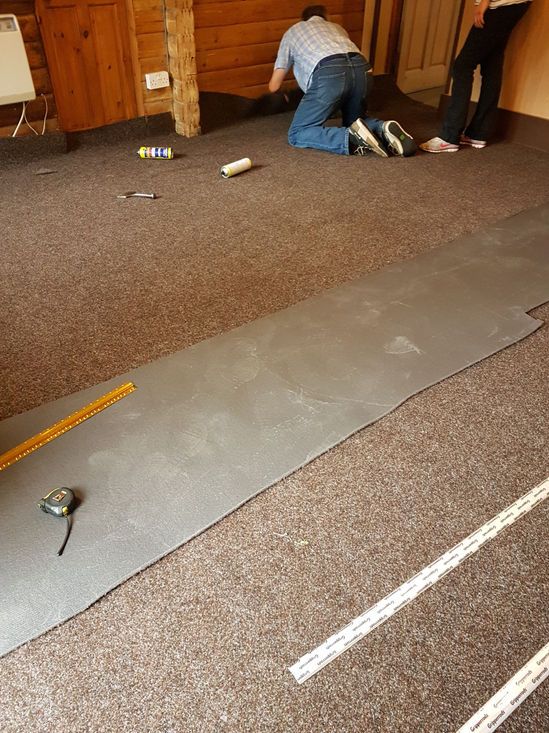 Team measuring and preparing carpet in room
