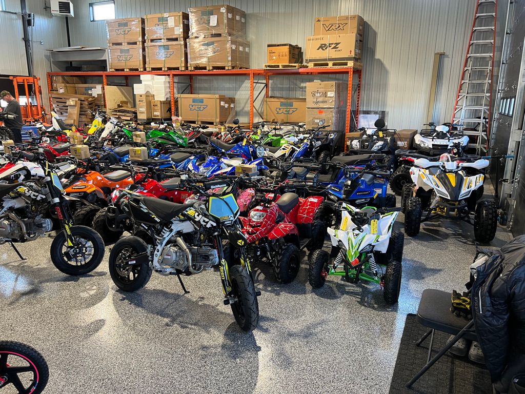 Warehouse or retail showroom with speckled grey epoxy floor packed with ATVs, motorbikes and shelving
