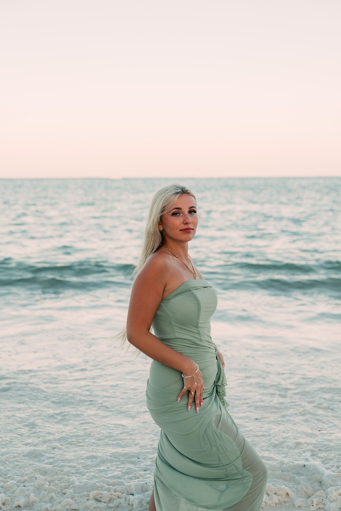 Woman in light green dress by the ocean at golden hour