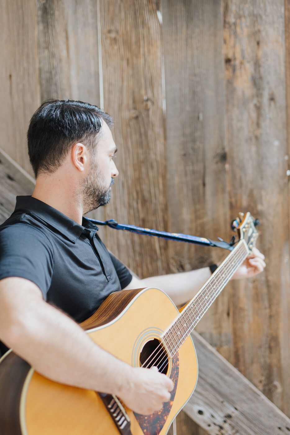 Tyler playing acoustic guitar — side profile