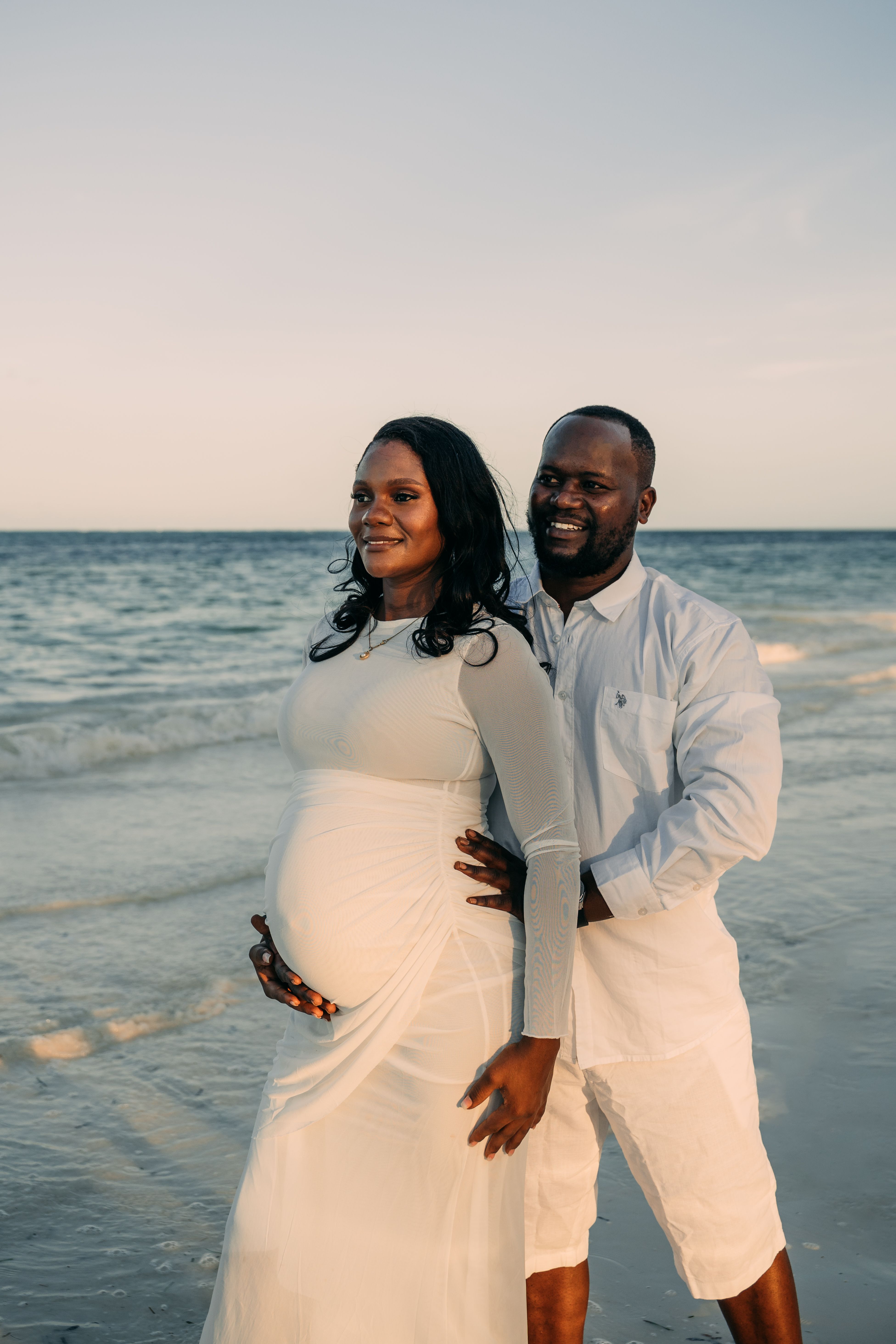 Maternity couple photoshoot on Zanzibar beach - man holding pregnant belly from behind