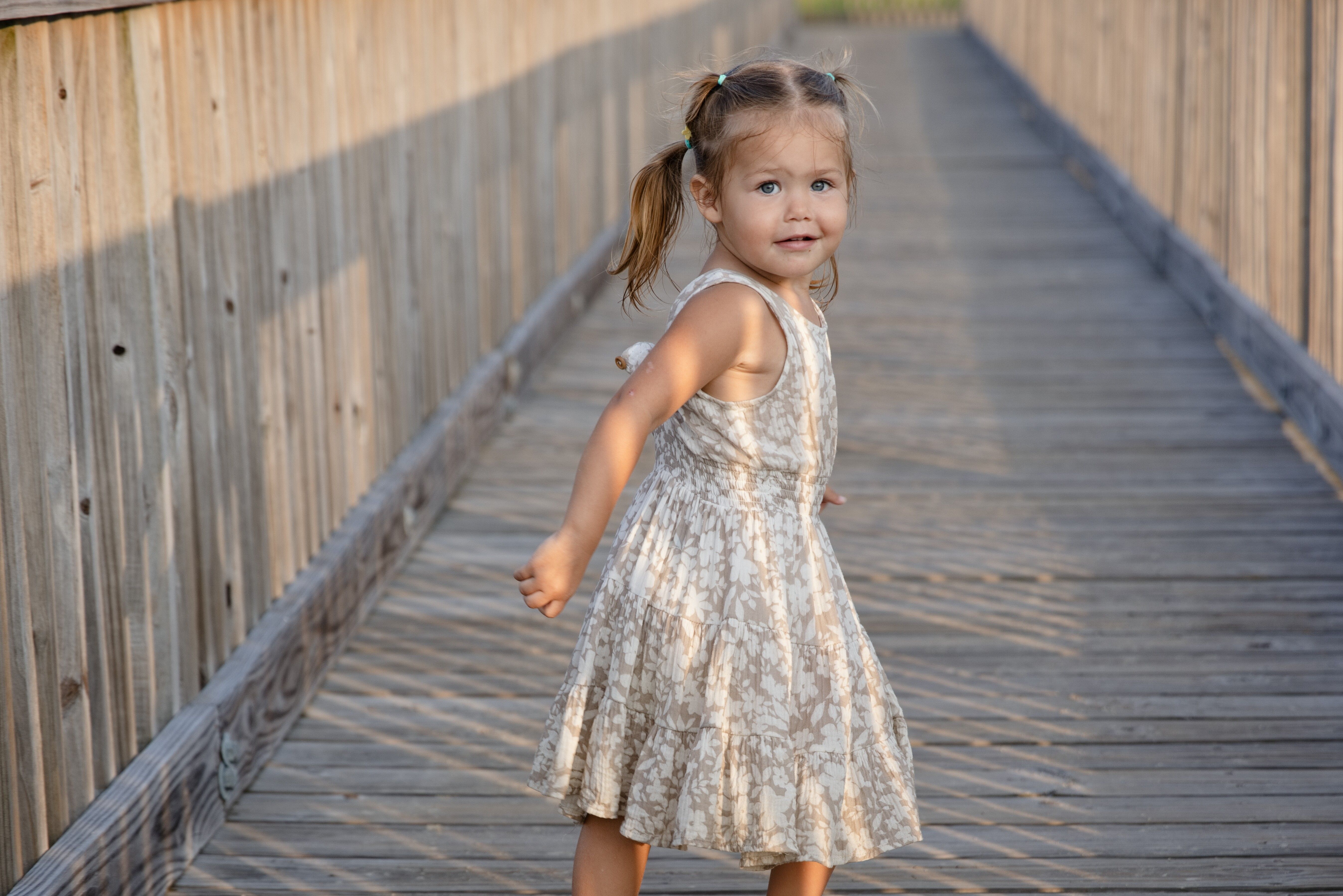 Little girl on a boardwalk looking back at the camera