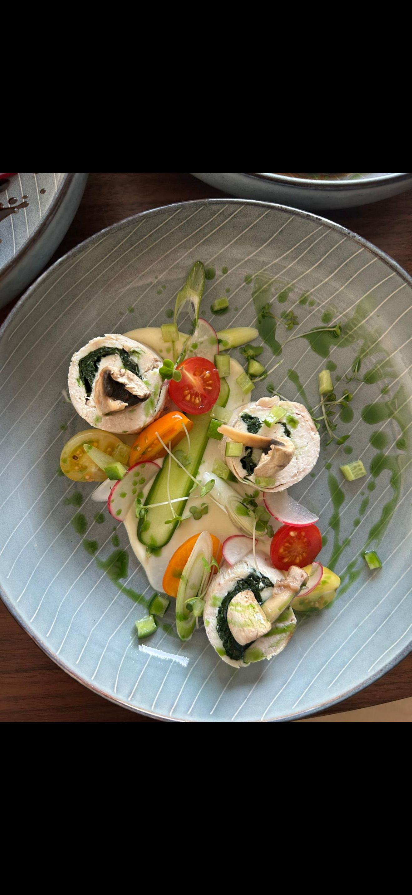 Stuffed meat roulade with seasonal vegetables and herb sauce