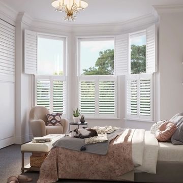 Beautiful bay window with white plantation shutters in a bright bedroom