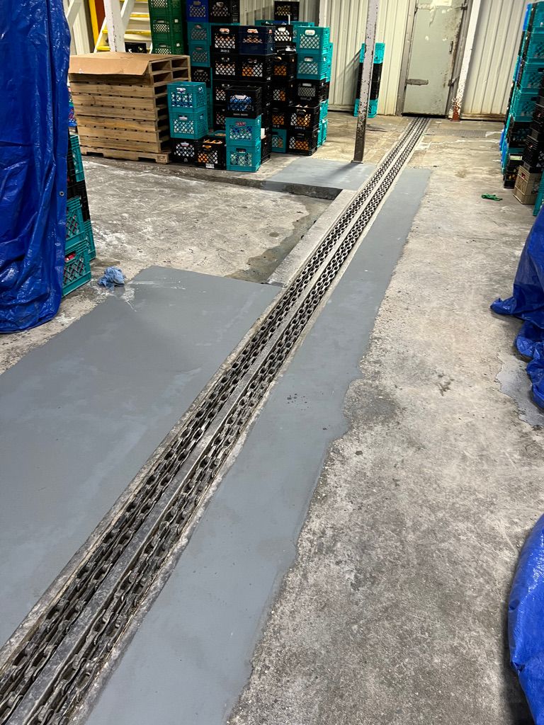 Concrete floor with metal drainage grate and patch repair in food processing facility