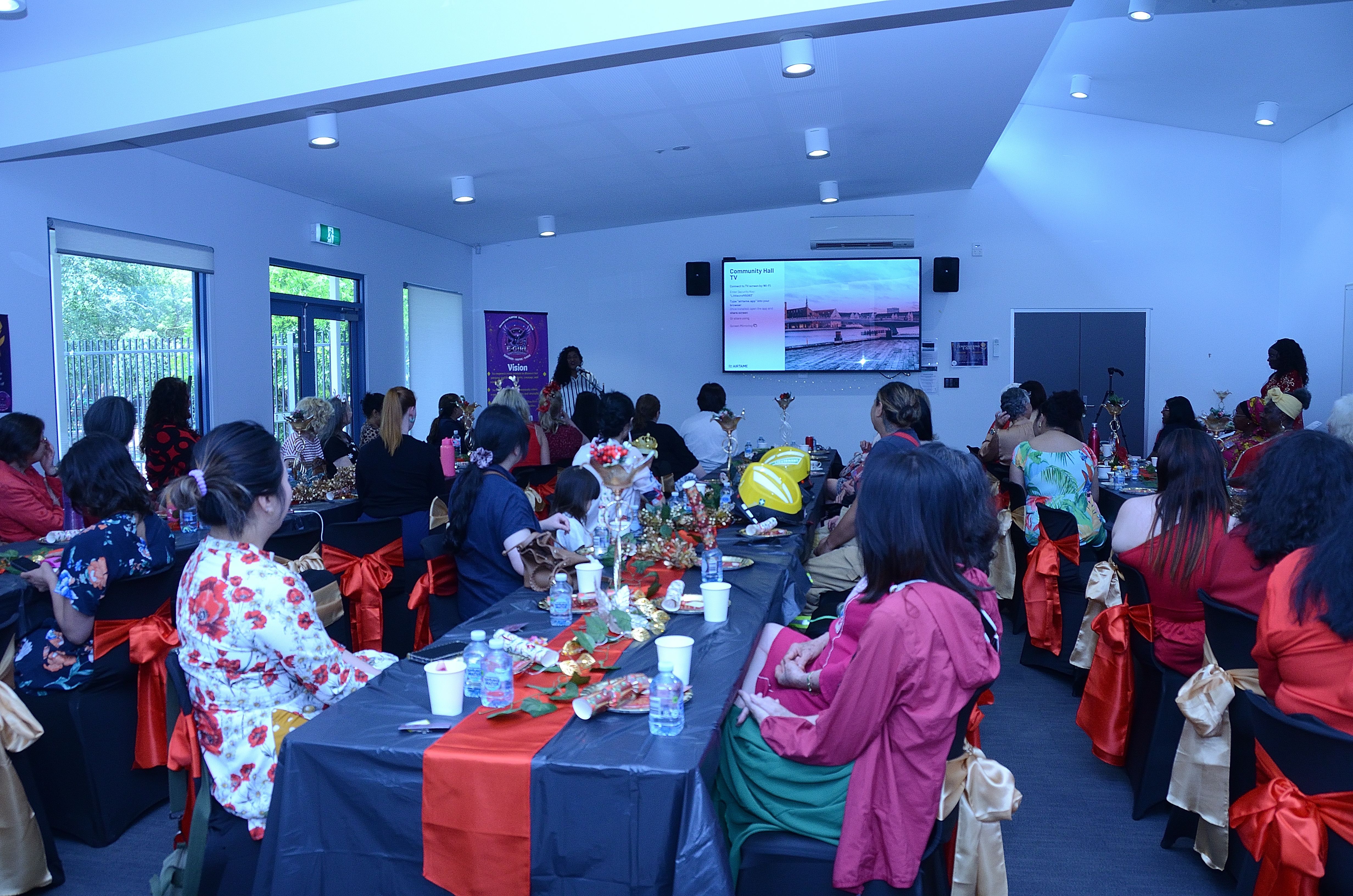 Women gathered at E-Girl Empowerment community event in Melbourne, watching a presentation together