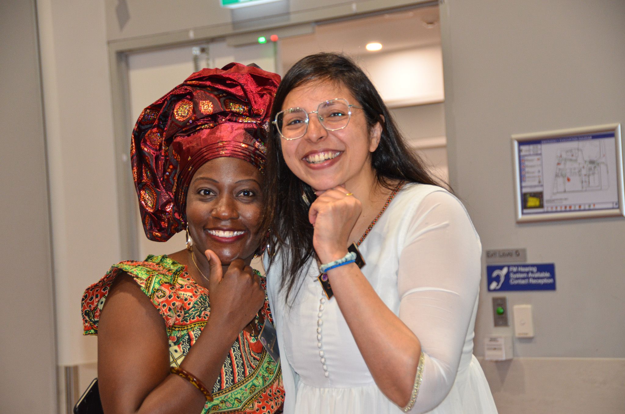 Two women smiling together in colourful traditional dress at E-Girl Empowerment community event