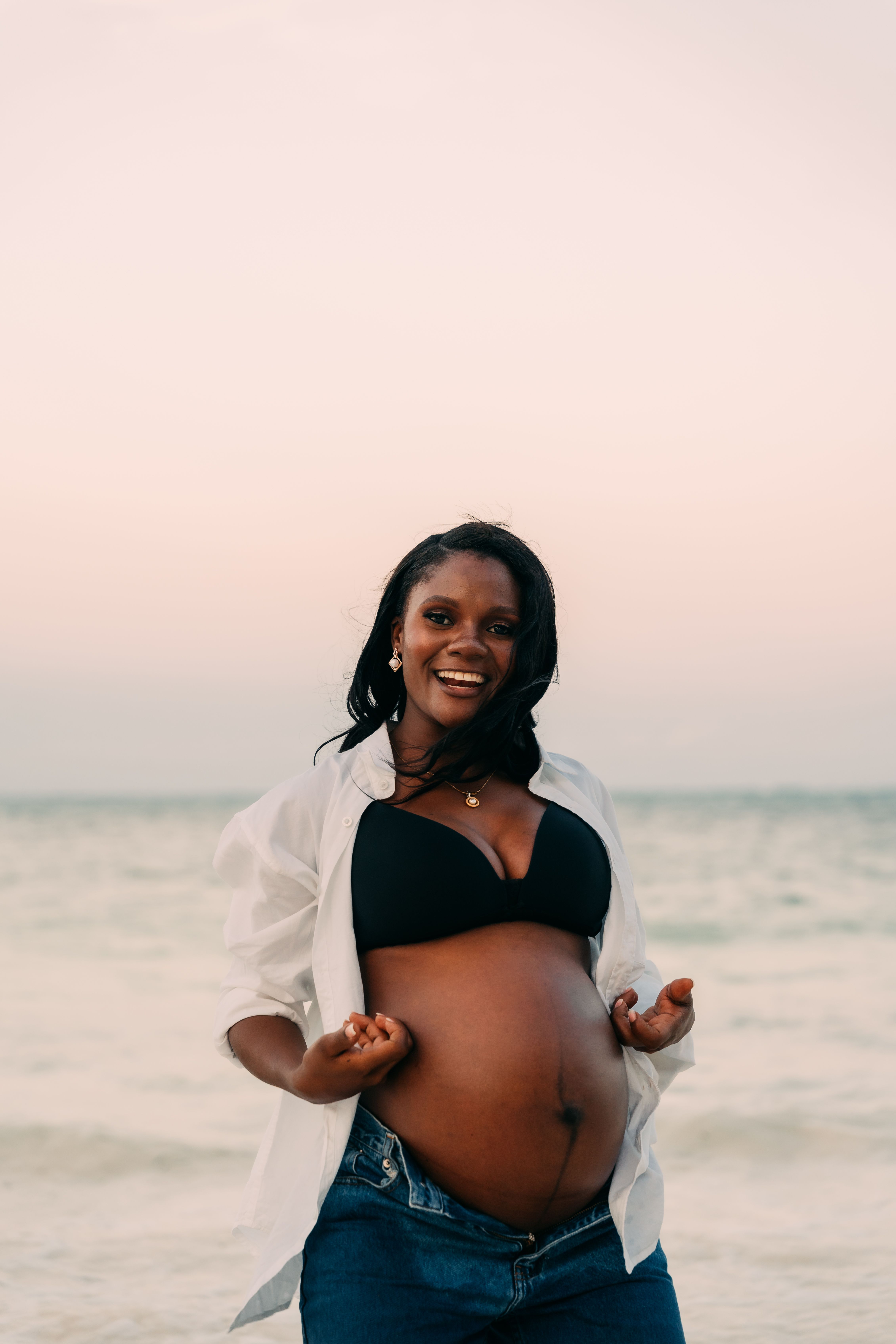 Pregnant woman smiling on Zanzibar beach in casual outfit - maternity session