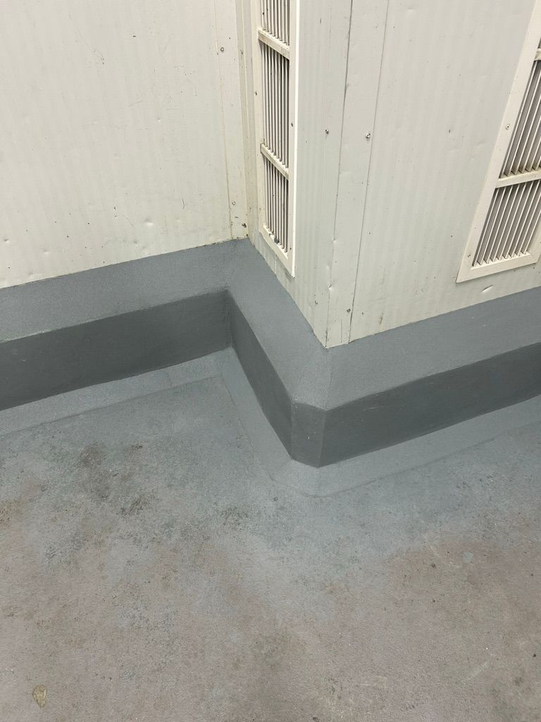 Restored commercial room corner with smooth gray seamless floor and cove base, white ridged walls and ventilation grilles