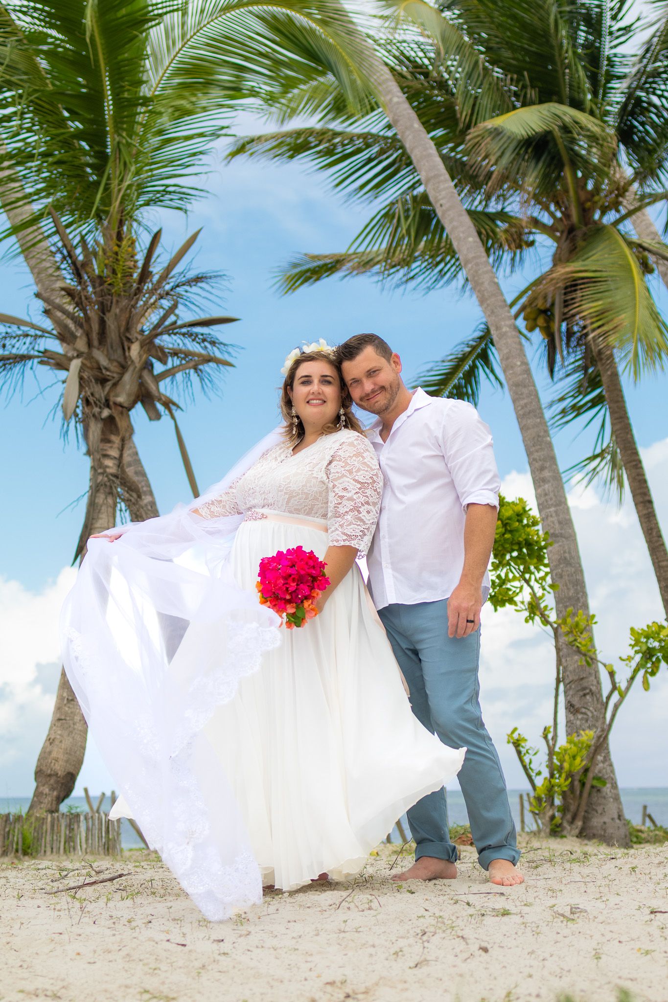 Couple smiling with pink bouquet and palm trees