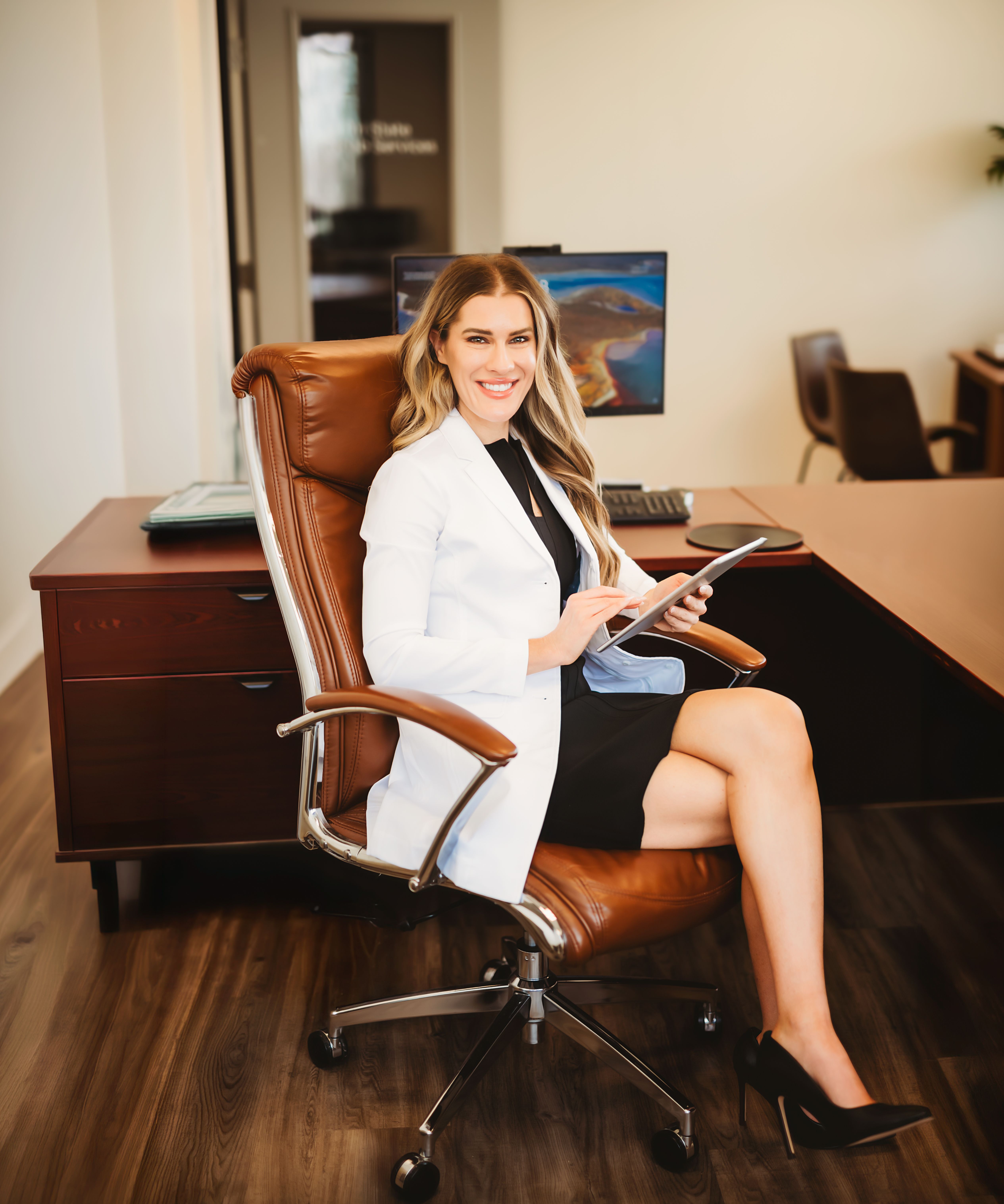 Michelle Perry, APRN, FNP‑C sitting at her office desk with tablet