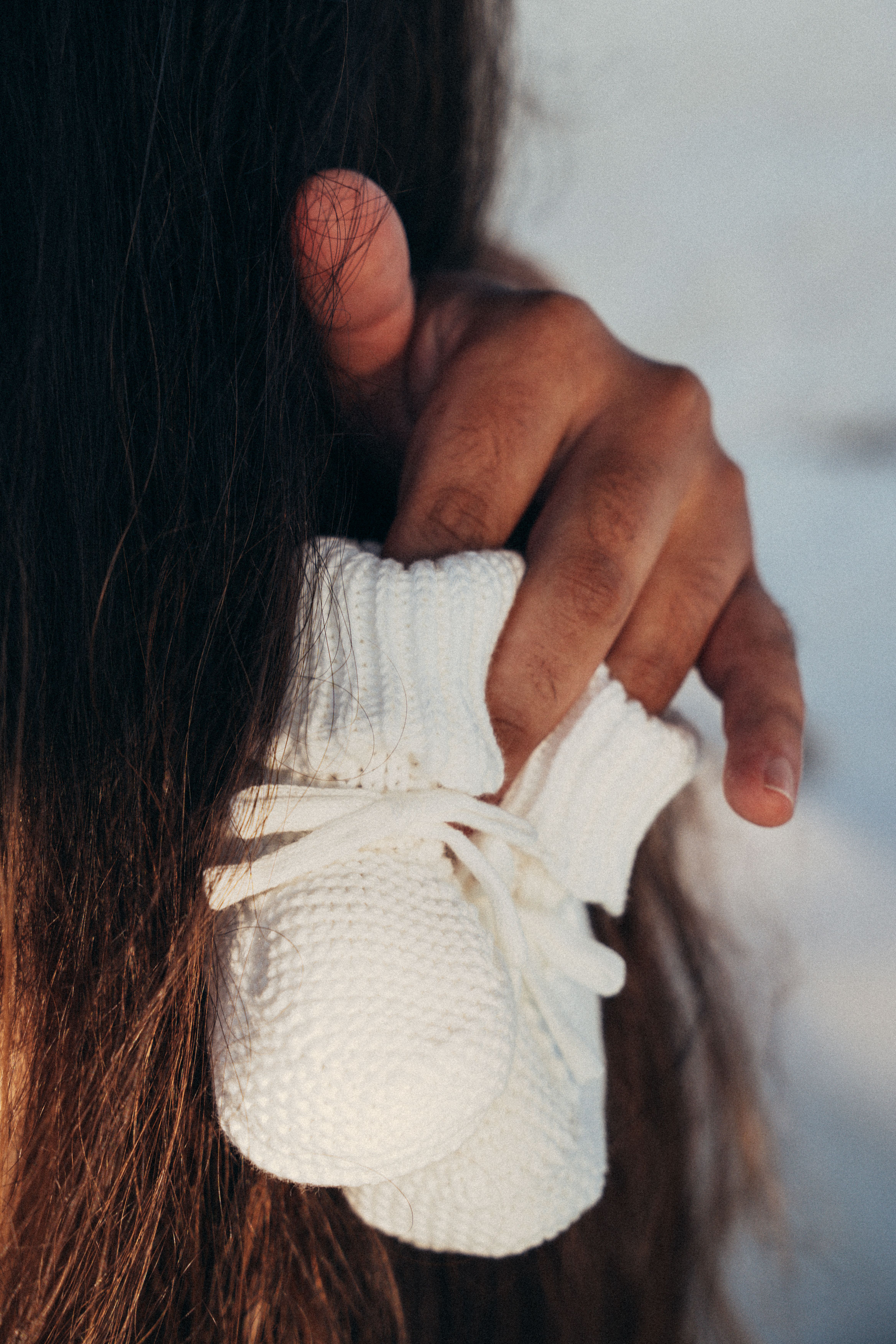 White knitted baby booties held in hand - maternity detail shot