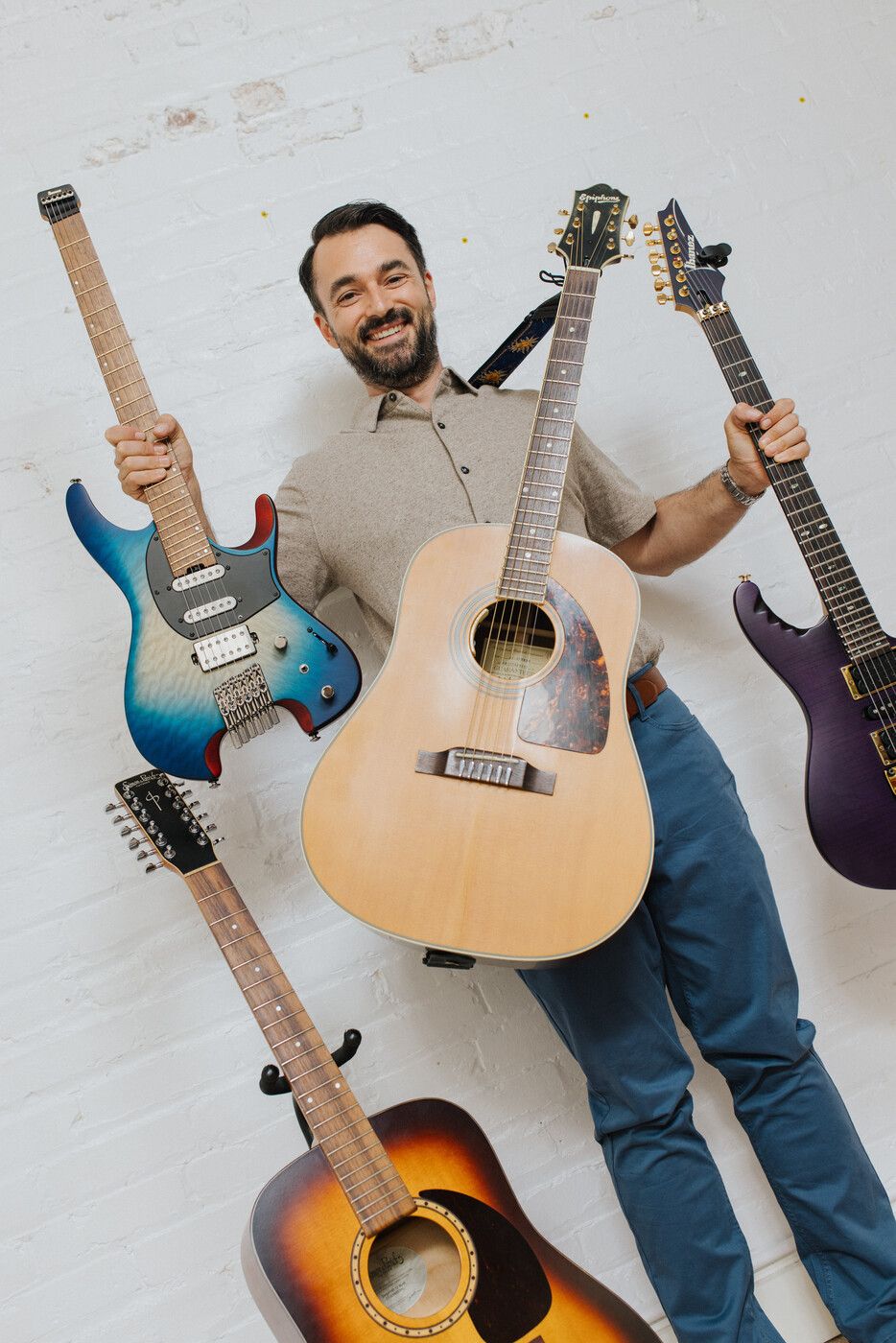 Tyler holding multiple guitars — electric, acoustic, and more
