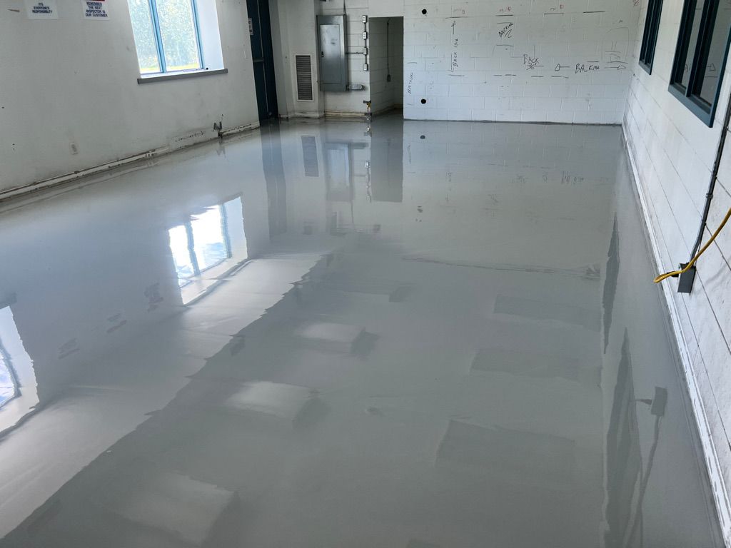 Empty room with highly reflective smooth gray ESD floor, white walls with technical markings, window on left wall