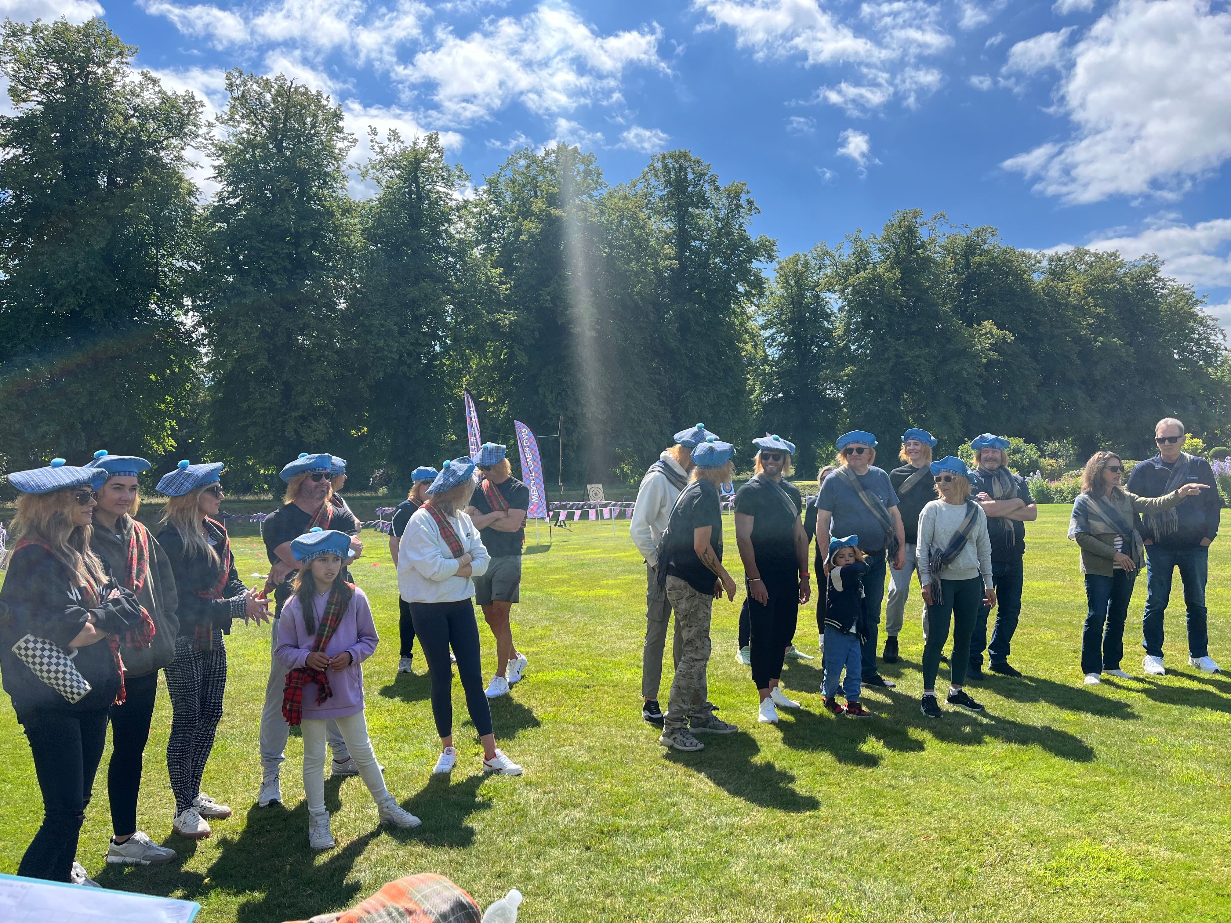 Guests in tartan scarves and blue berets at Highland Games pre-wedding celebration at Carnell Estate