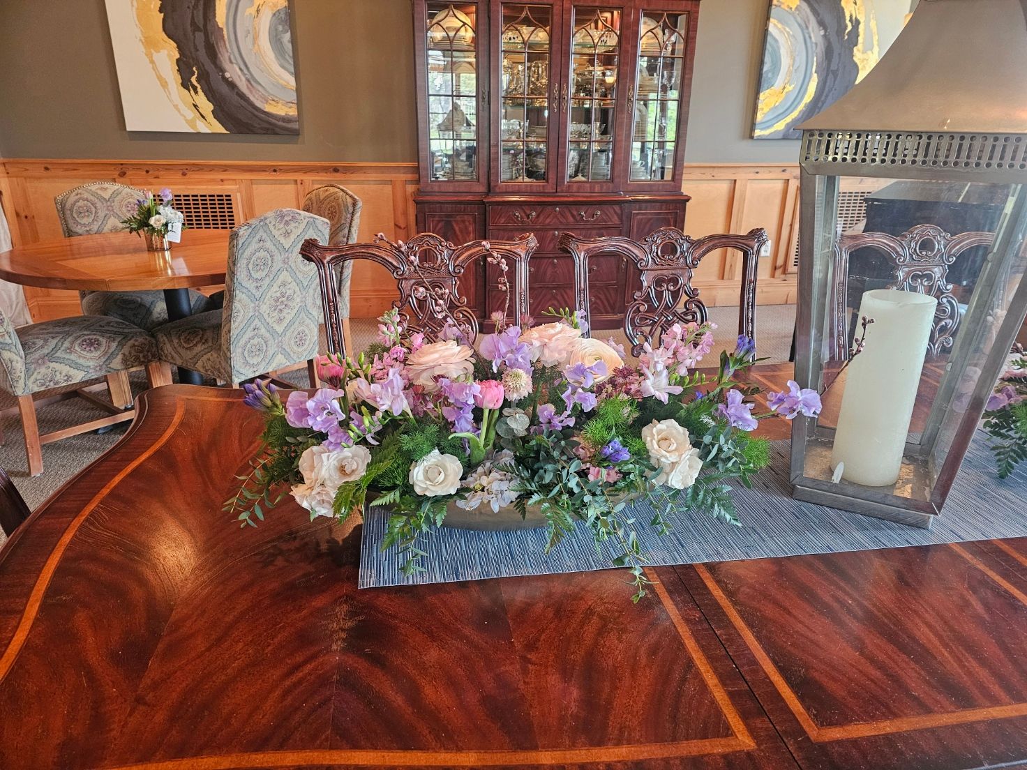 Polished dining table with ornate floral centerpiece and lantern at elegant venue