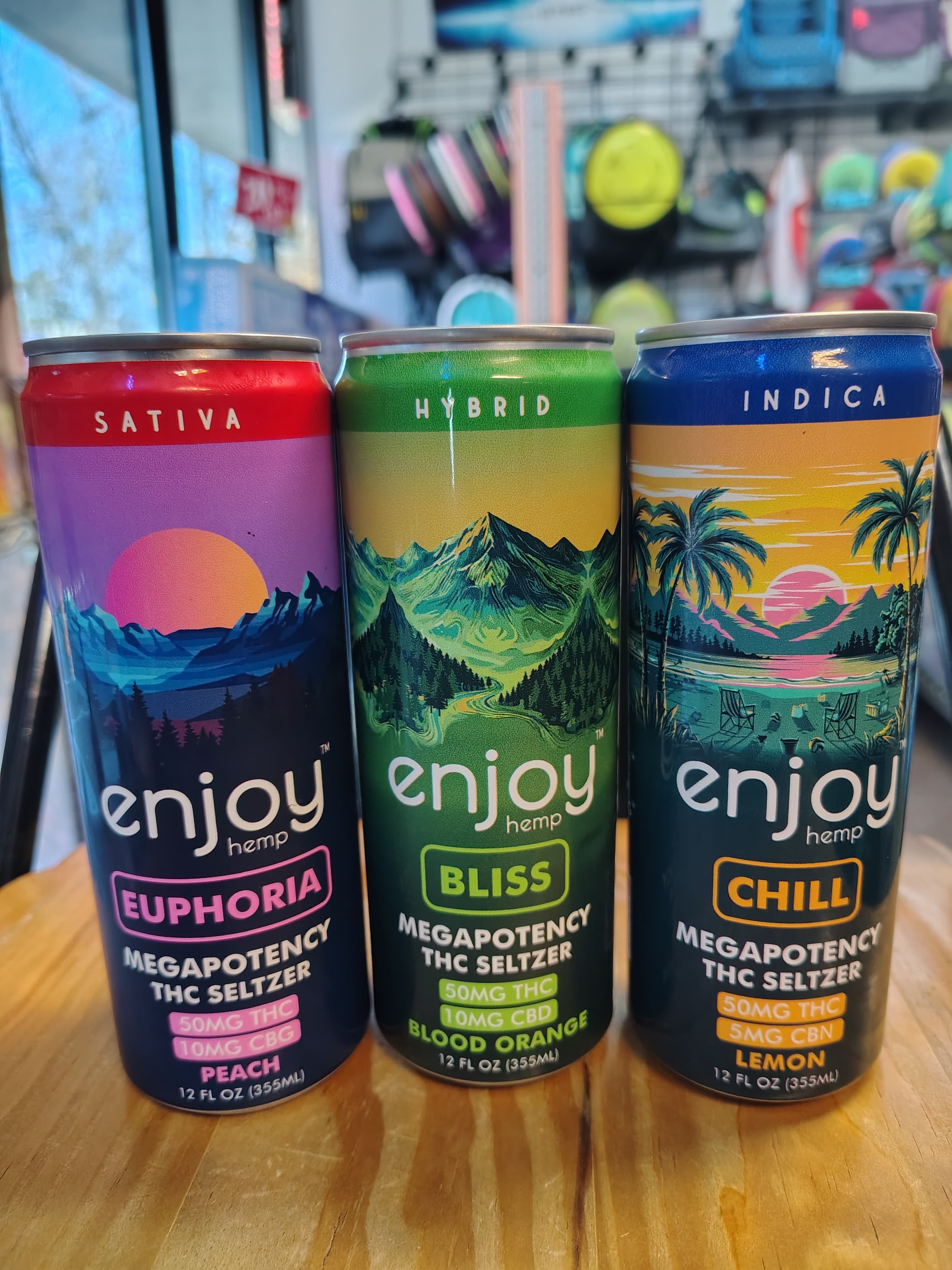 Enjoy Hemp THC Seltzer cans showing Sativa Euphoria, Hybrid Bliss, and Indica Chill flavors at Flowland Aberdeen NC