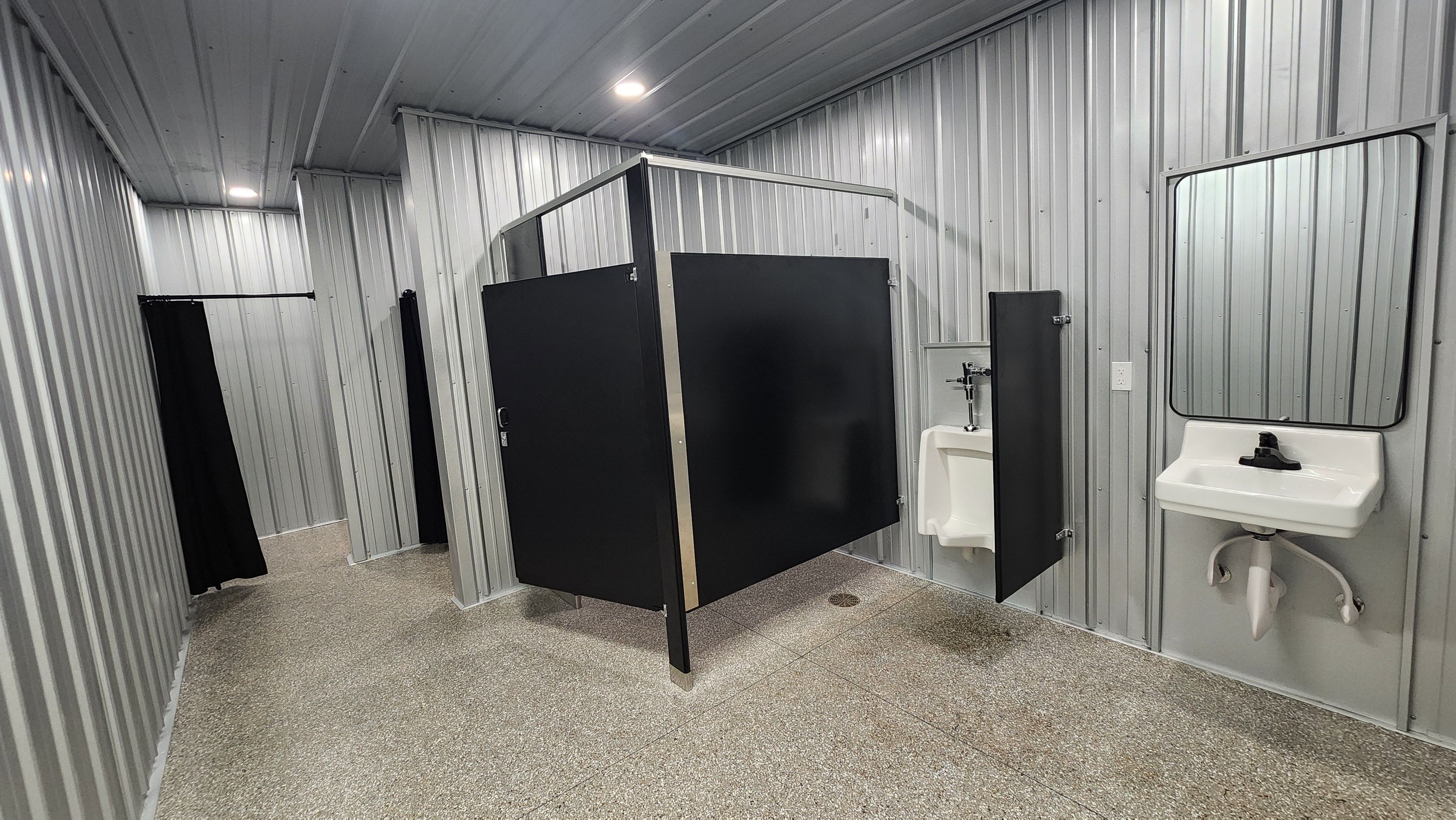 New restroom interior with stall, urinal, sink, and mirror at Welcome Woods