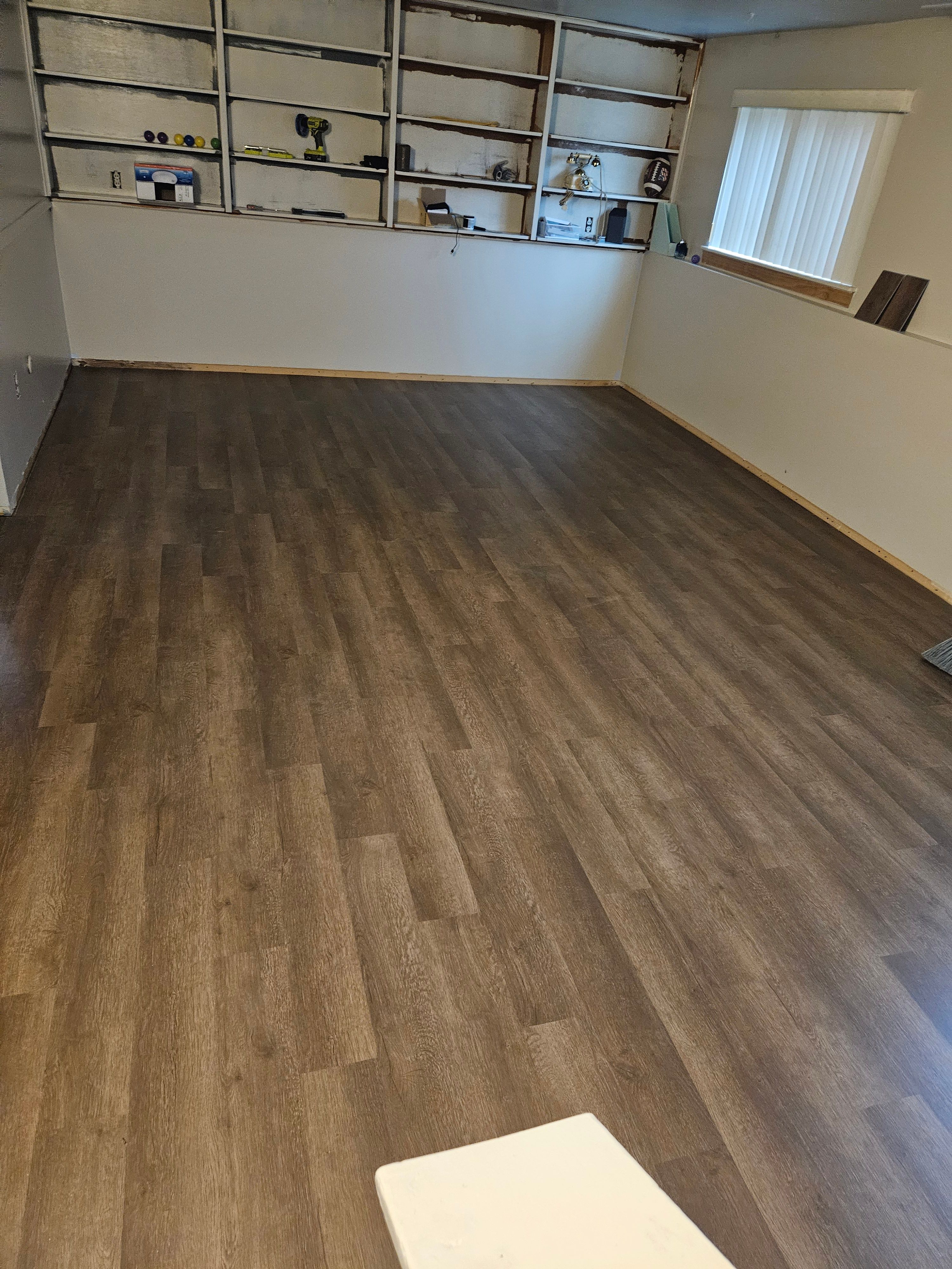 Finished basement room with new flooring and built-in shelving