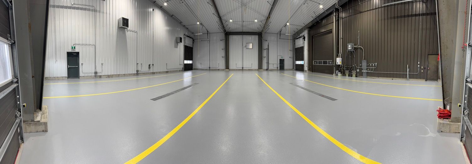 Plancher époxy gris avec lignes de délimitation jaunes dans une installation industrielle