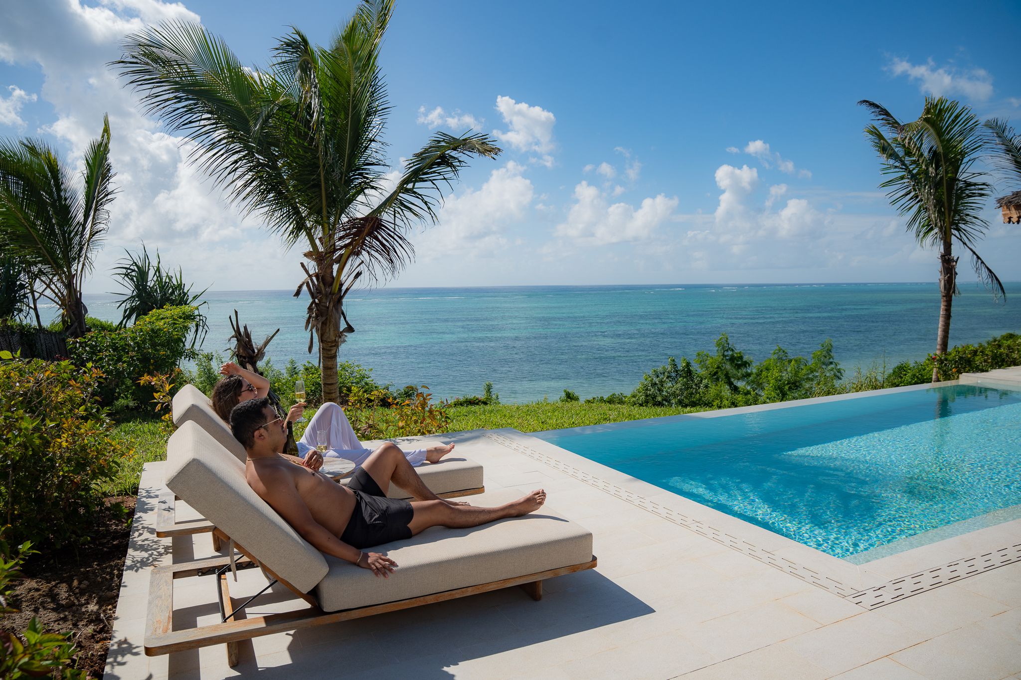 Couple relaxing by pool with ocean backdrop — vacation photography Zanzibar