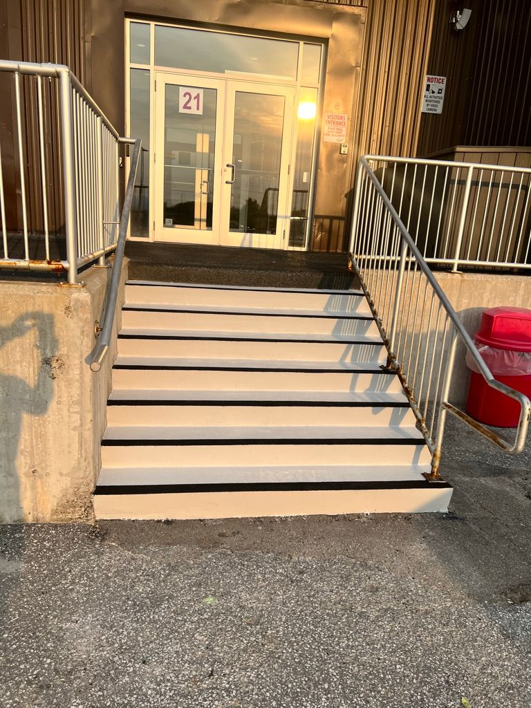 Restored white concrete staircase with black anti-slip edges leading to commercial visitors entrance