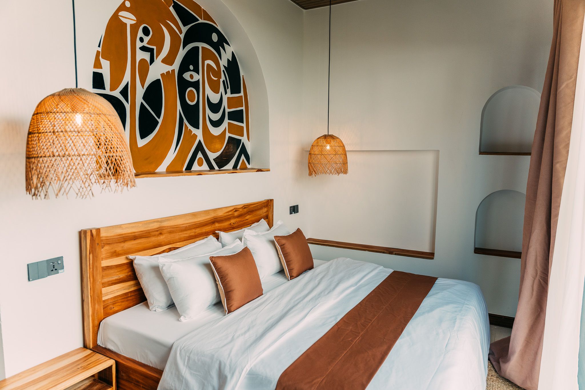 Bedroom with white sheets, wooden headboard and wicker pendant lamps — small hotel room photography Zanzibar