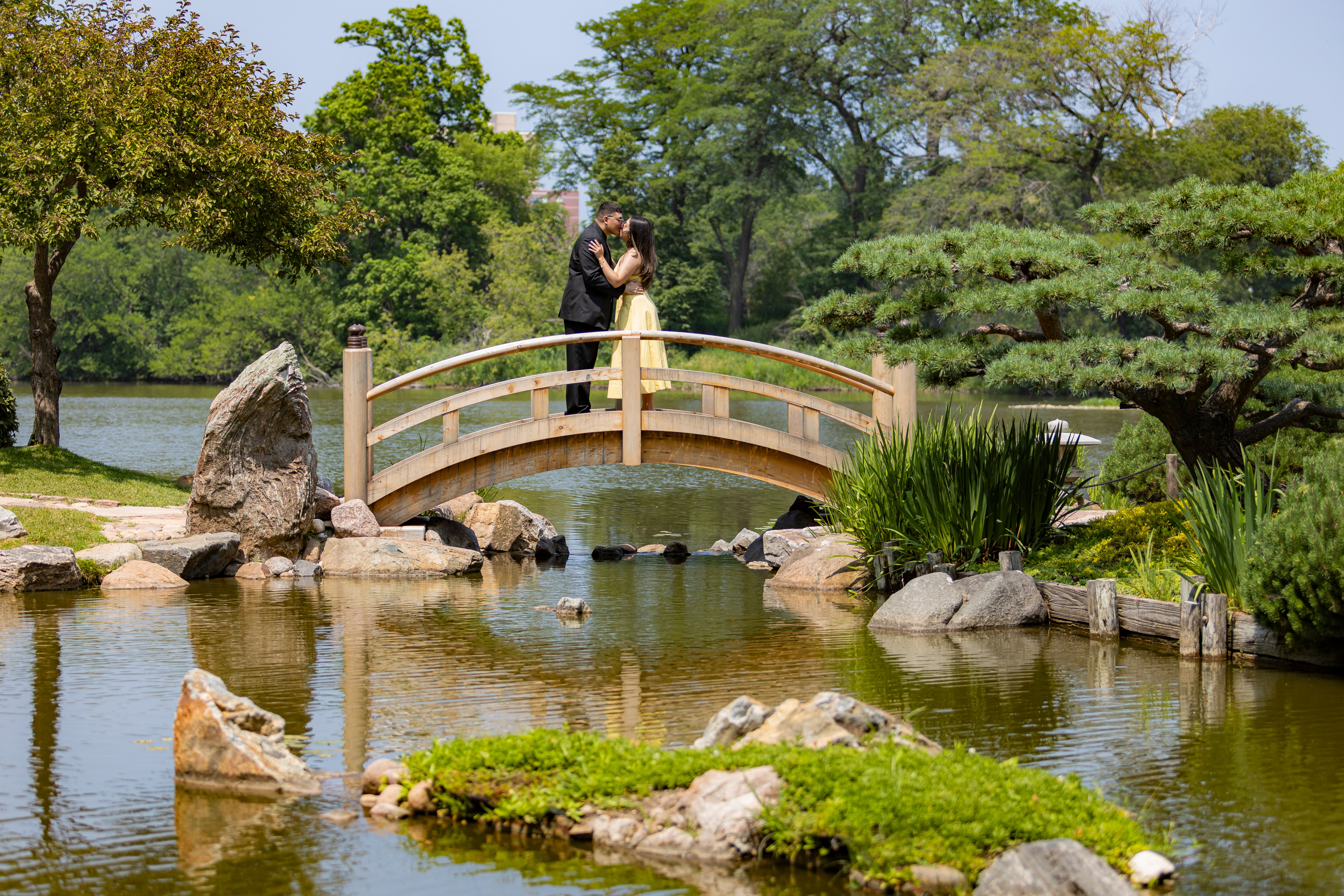 Couple kissing on wooden bridge over pond