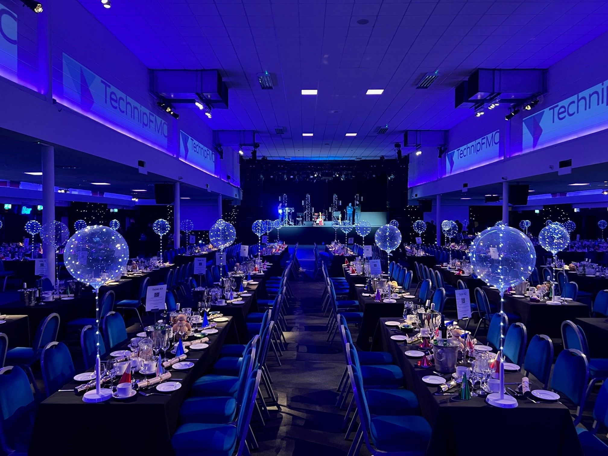 TechnipFMC corporate Christmas party gala dinner with blue lighting and branded banners — Event Collection UK