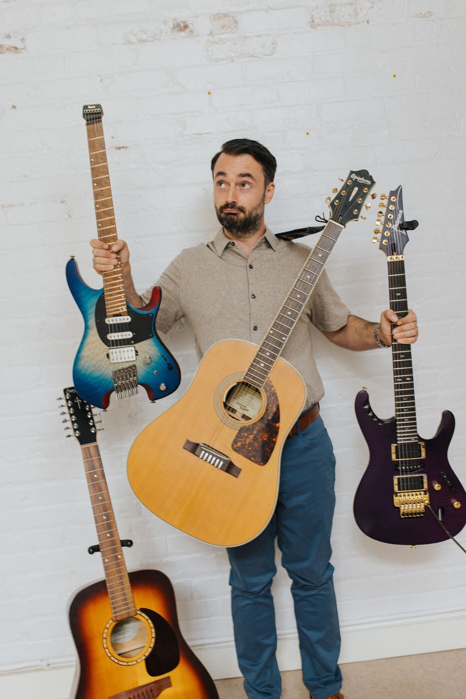 Tyler standing with multiple guitars — guitar buying and sourcing guidance