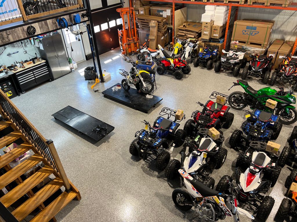 Indoor garage showroom with polished epoxy floor and ATVs and dirt bikes organized throughout