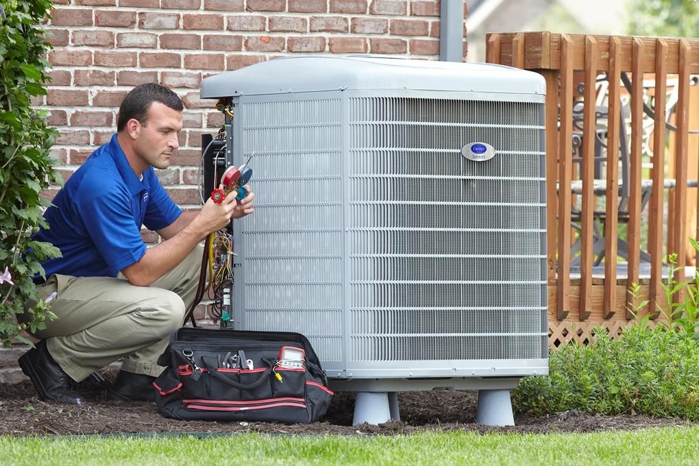 HVAC technician checking refrigerant gauges on an outdoor AC unit during an inspection