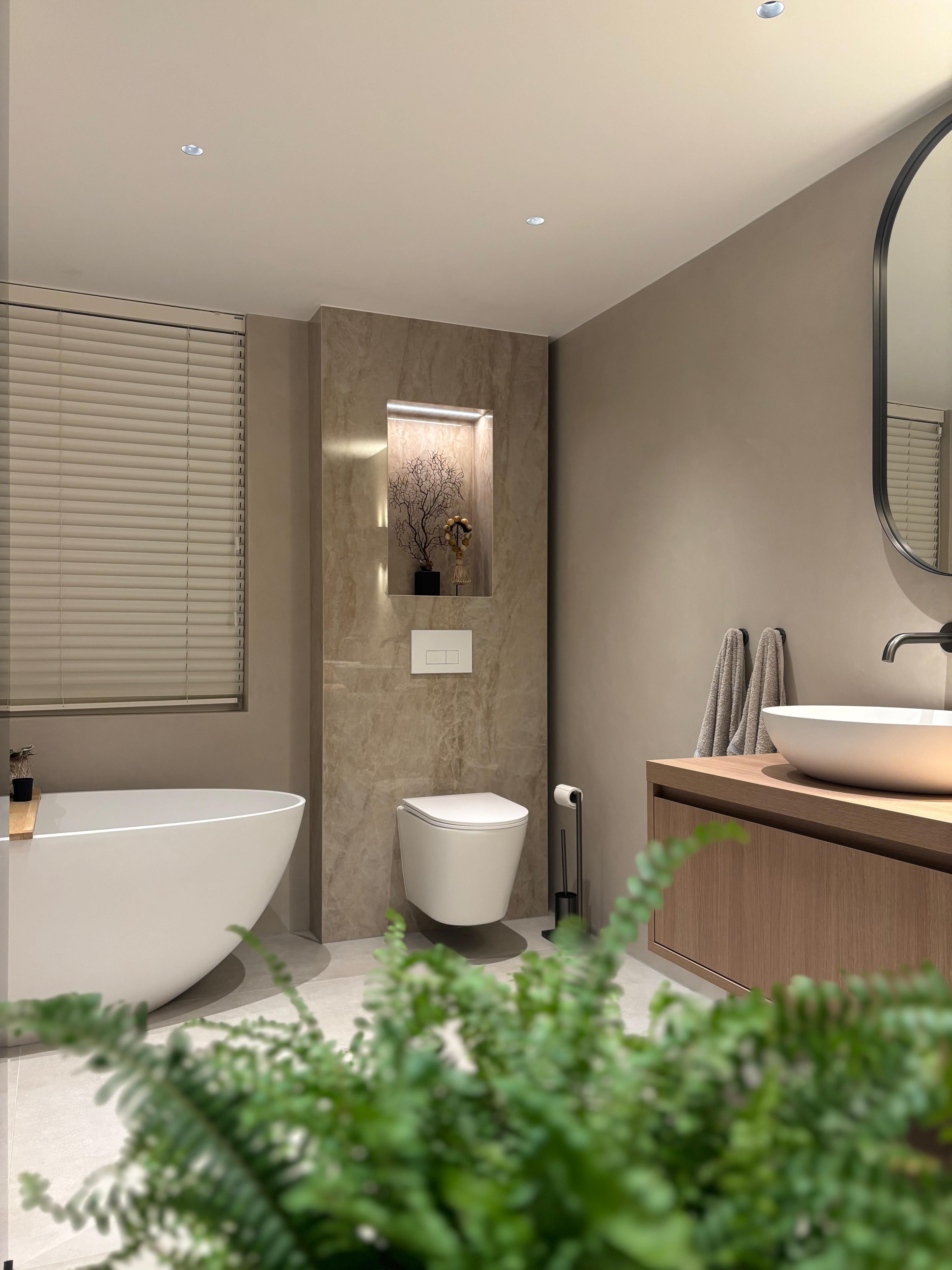 Luxe badkamer Bergen op Zoom met vrijstaand bad, houten wastafelmeubel en decoratieve nis — Jerry's Tegelwerken