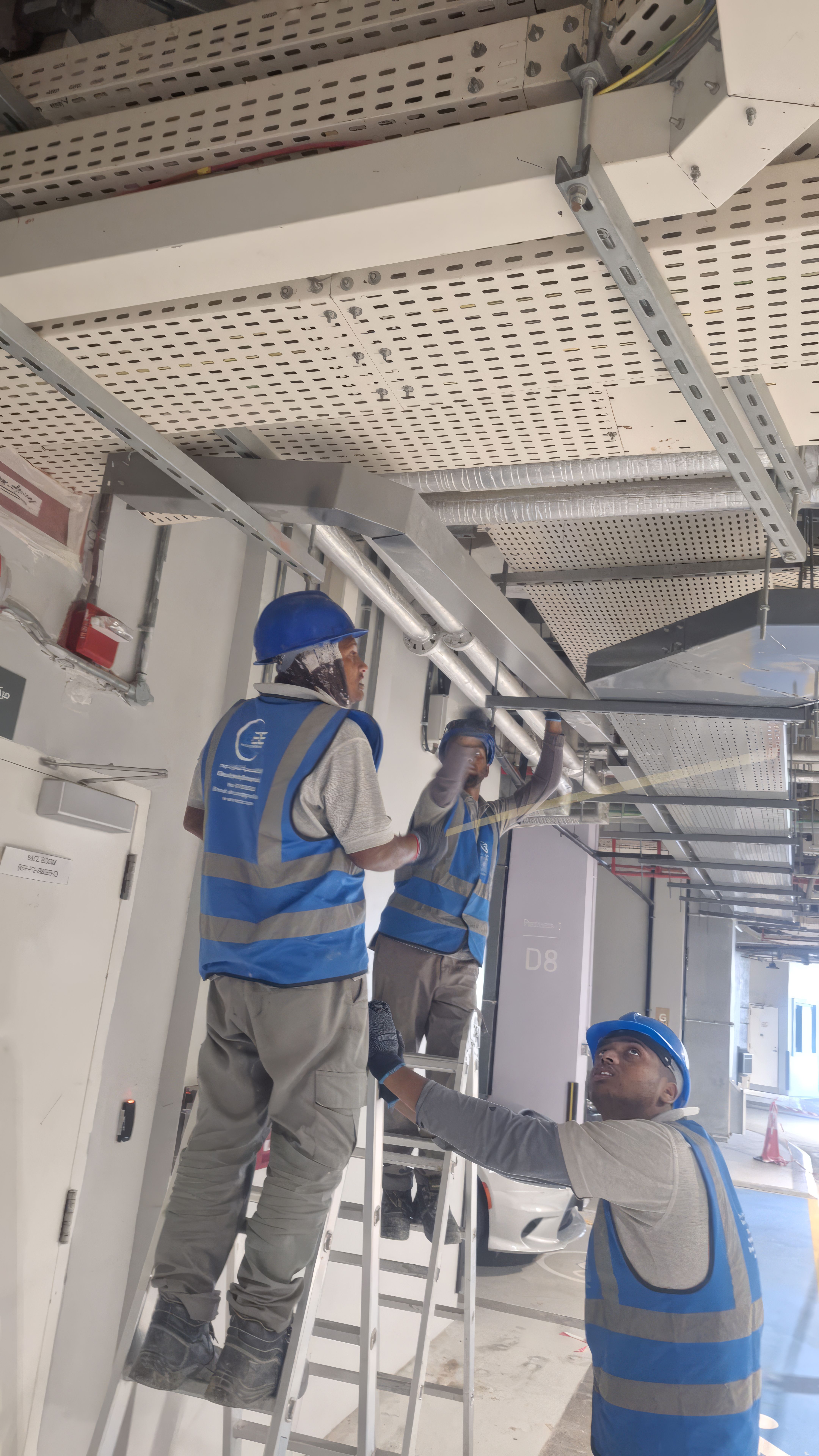 ELCO team in branded blue vests and helmets installing ceiling panels