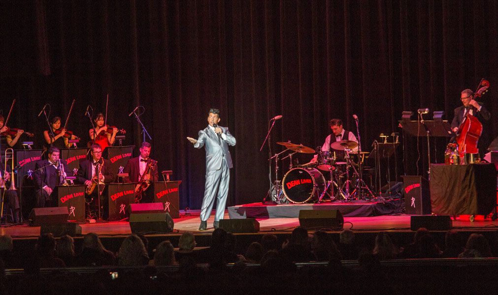 Drew Anthony as Dean Martin in silver suit performing center stage