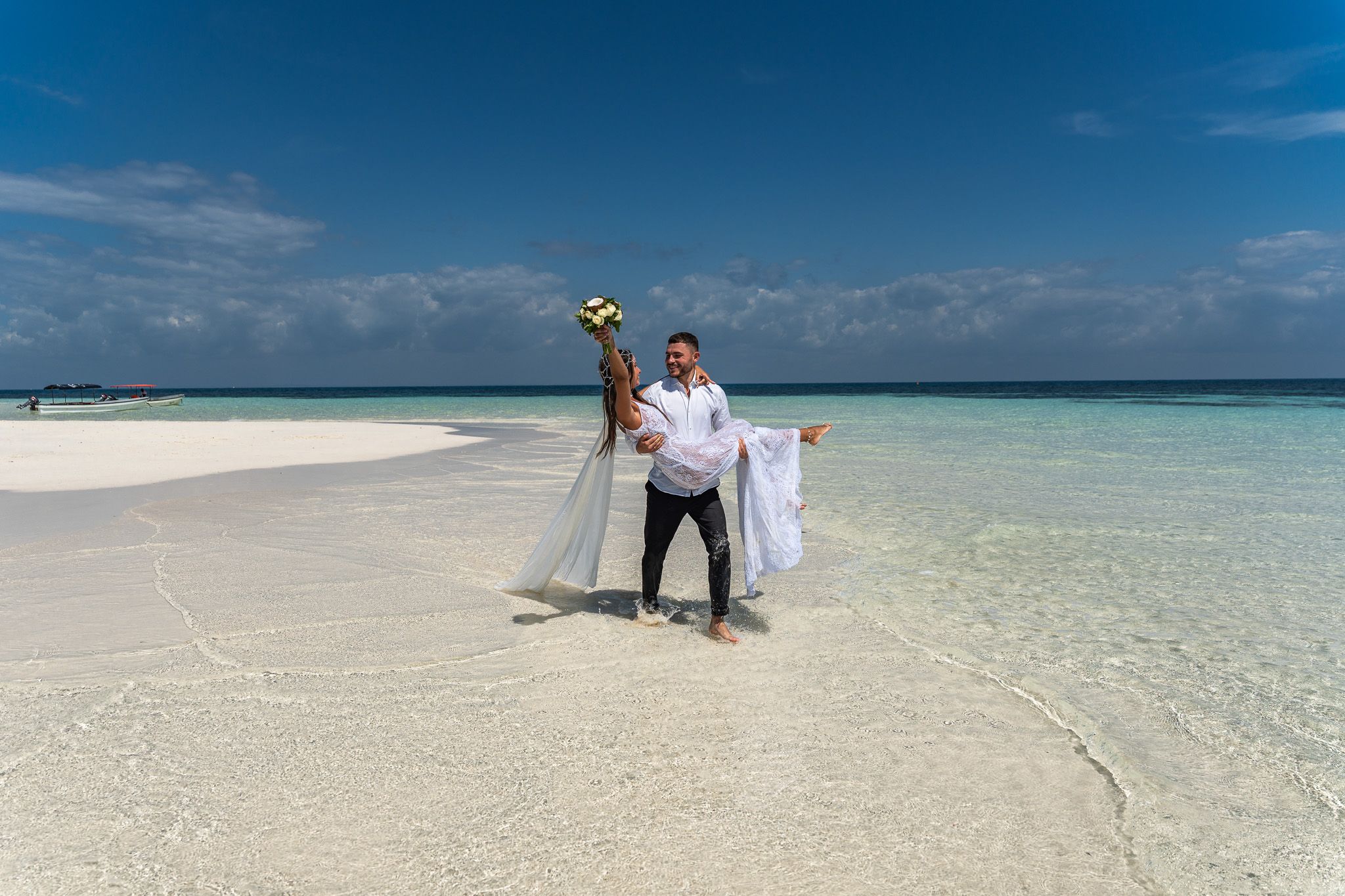 Couple in crystal clear water with bouquet - sandbank photoshoot Zanzibar