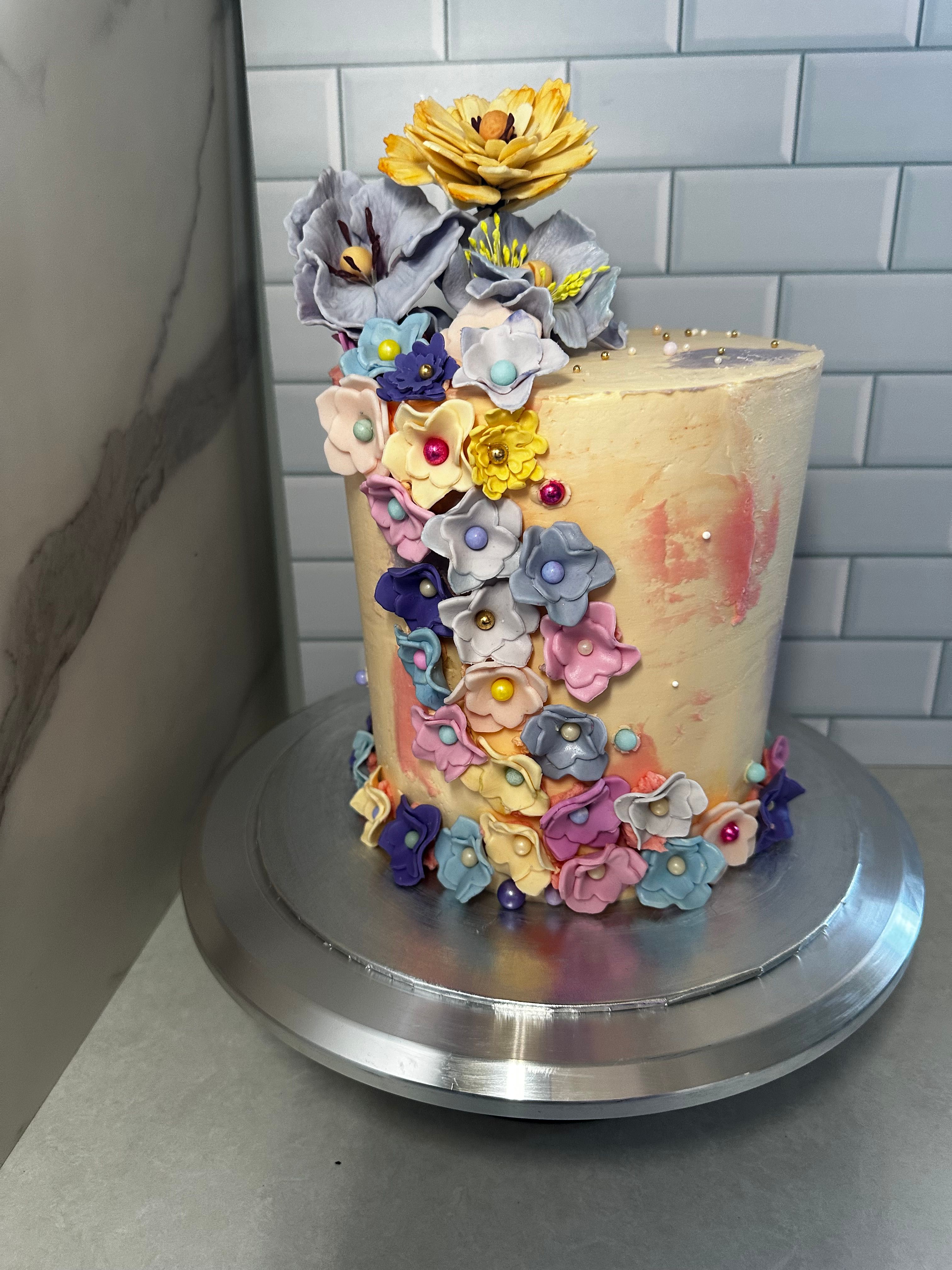 Tall celebration cake with cascading colourful buttercream flowers