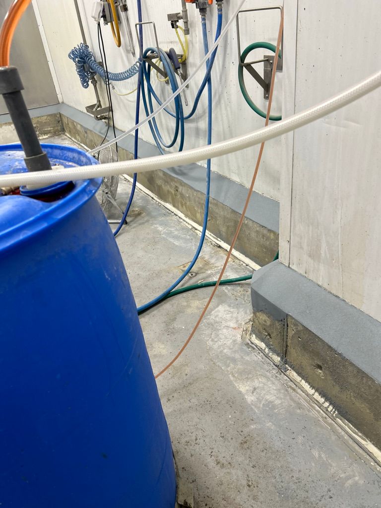 Concrete floor repair area with single injection barrel and multiple hose lines connected to wall fittings