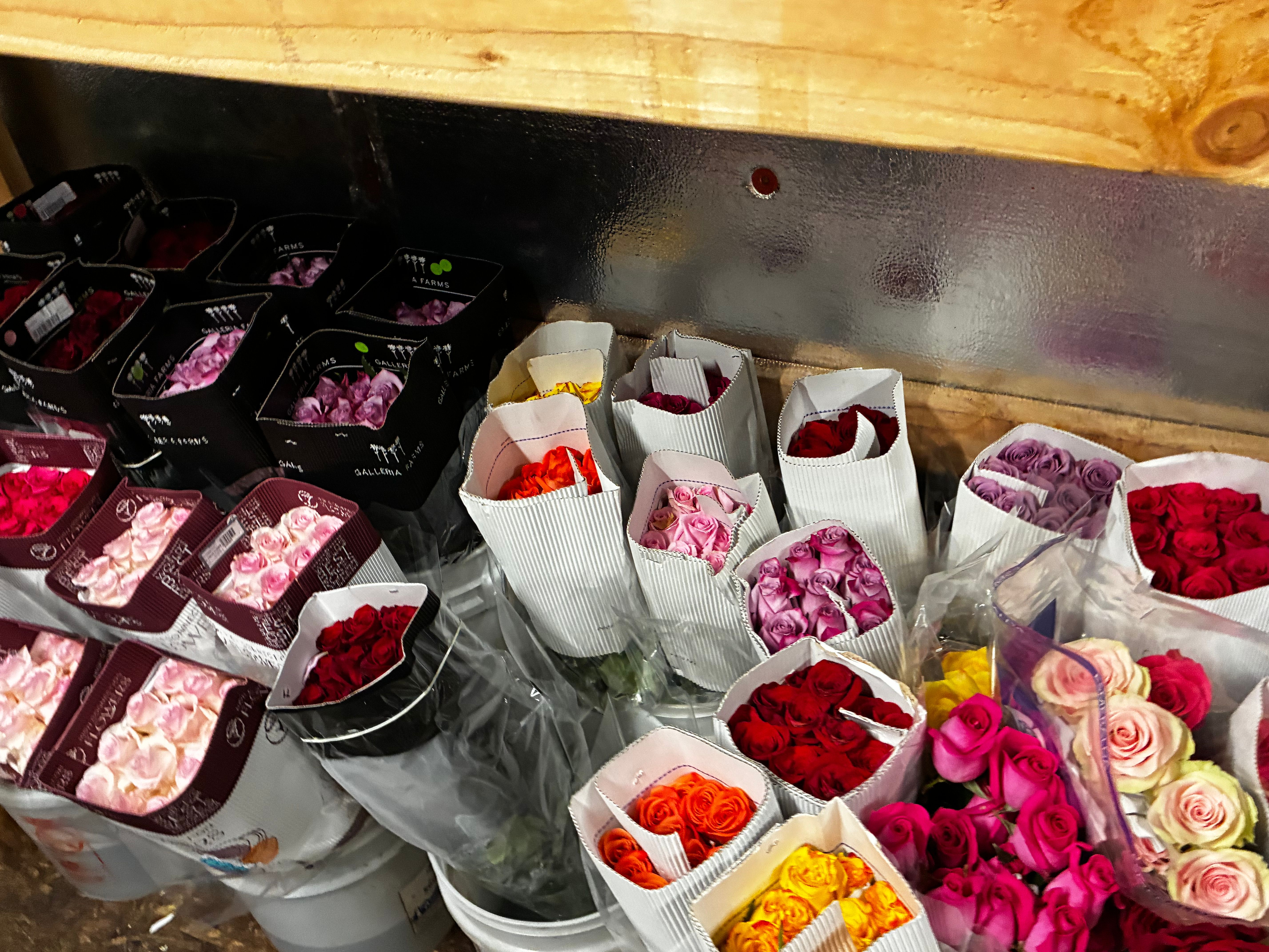 Colorful bouquets of roses in white buckets โ red, pink, orange, yellow, purple