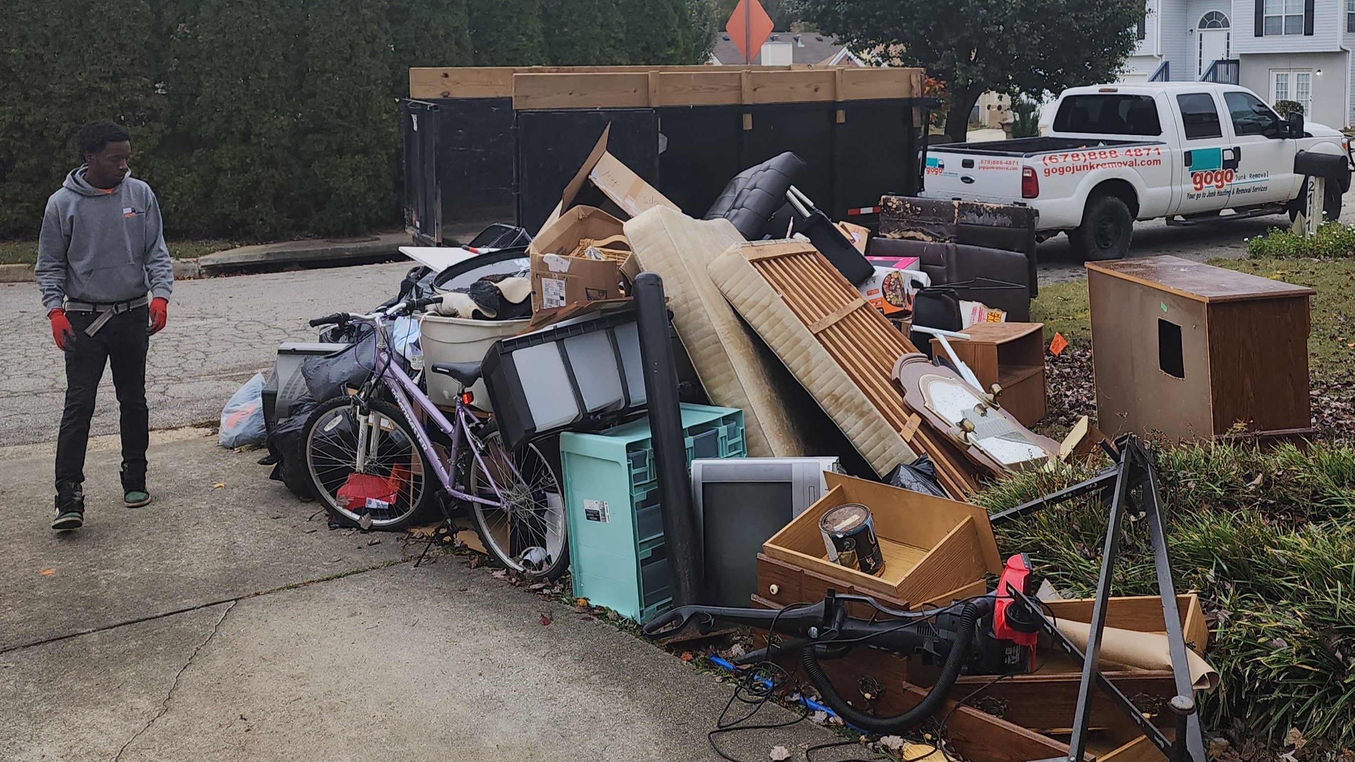 GoGo crew member standing next to large pile of household junk and furniture ready for removal