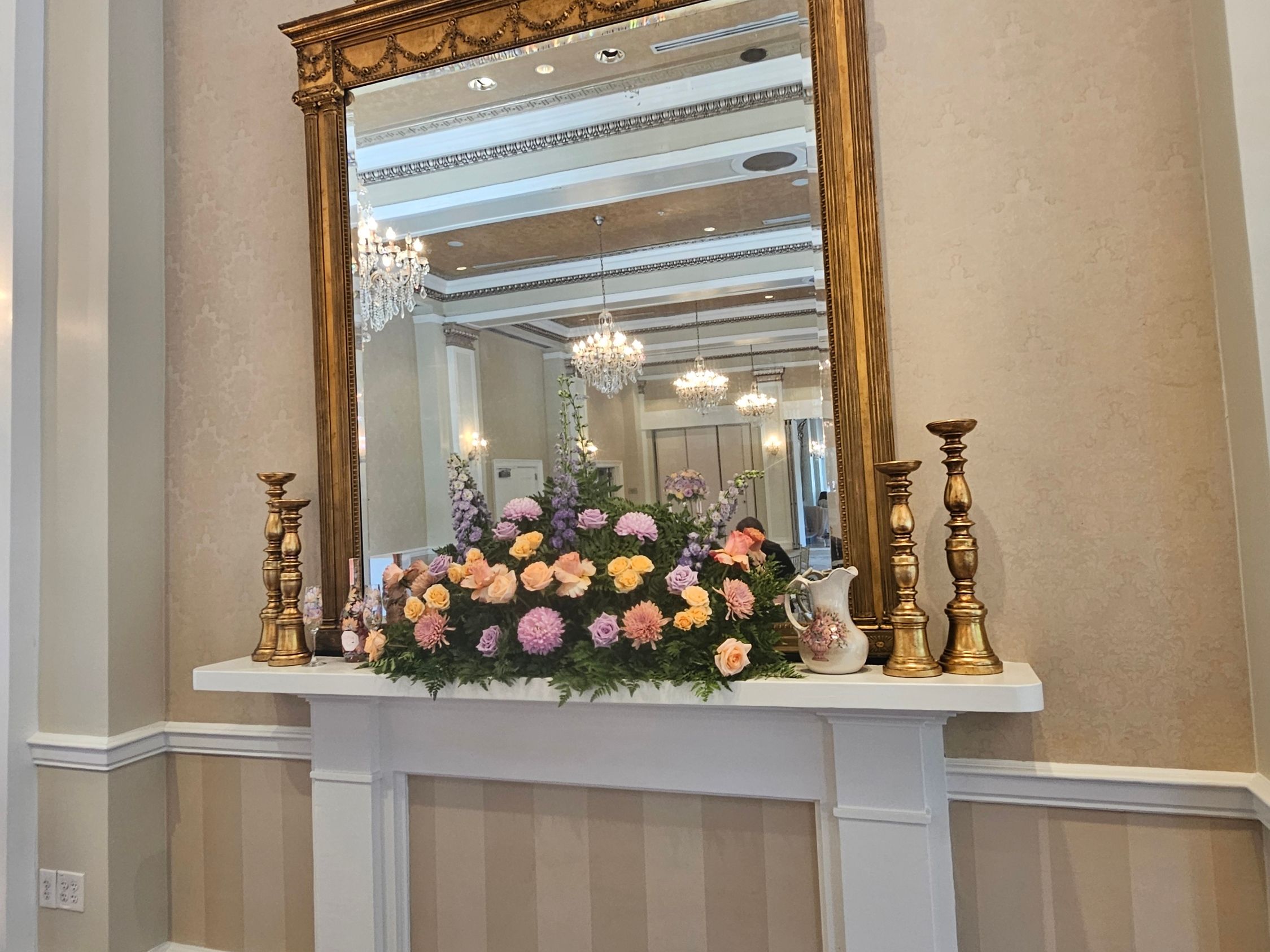 Grand mantle floral installation with gold candlesticks and mirror at historic venue