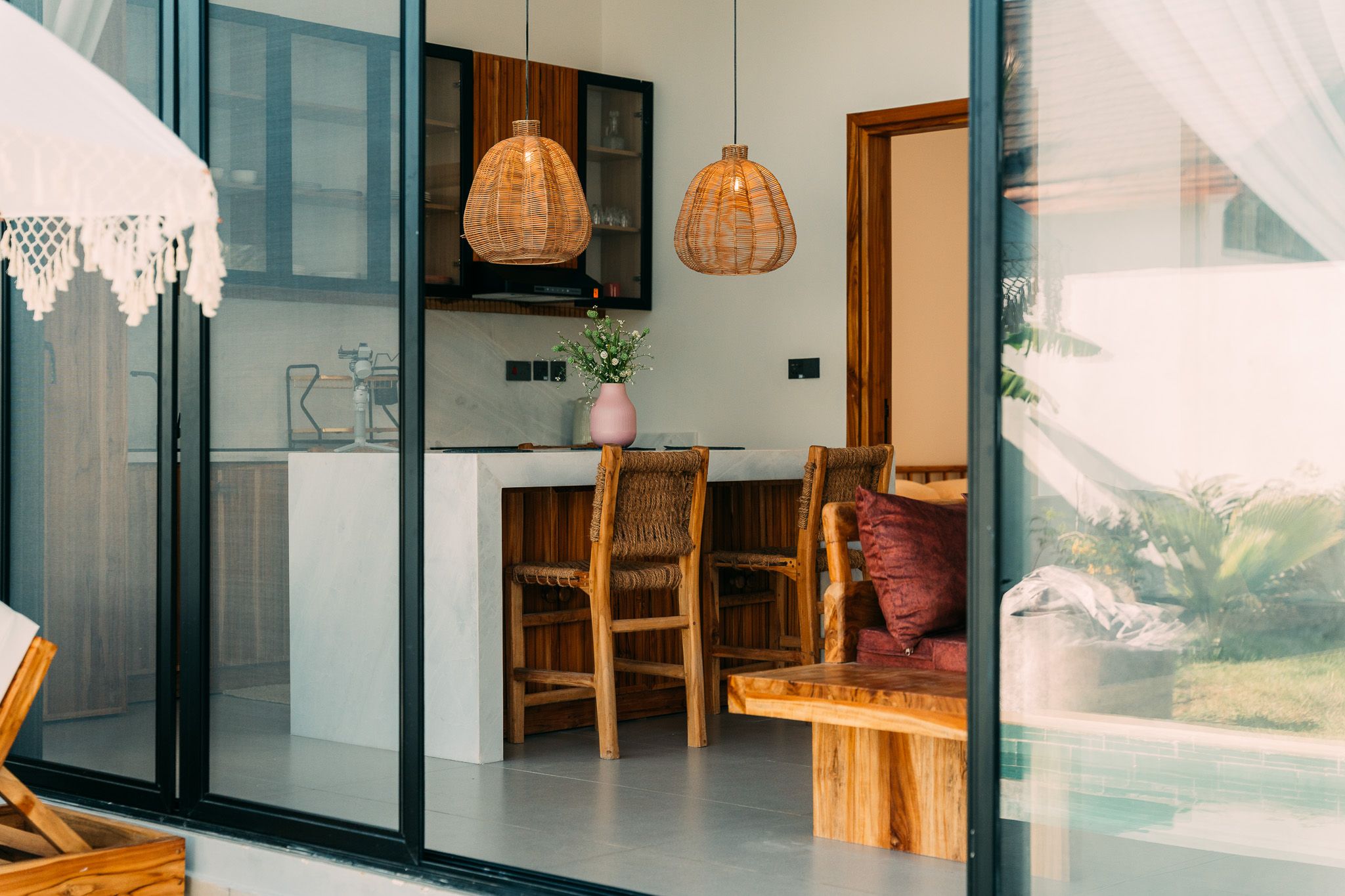 Modern kitchen interior with island, wicker pendant lights and flowers — Airbnb property photography Zanzibar